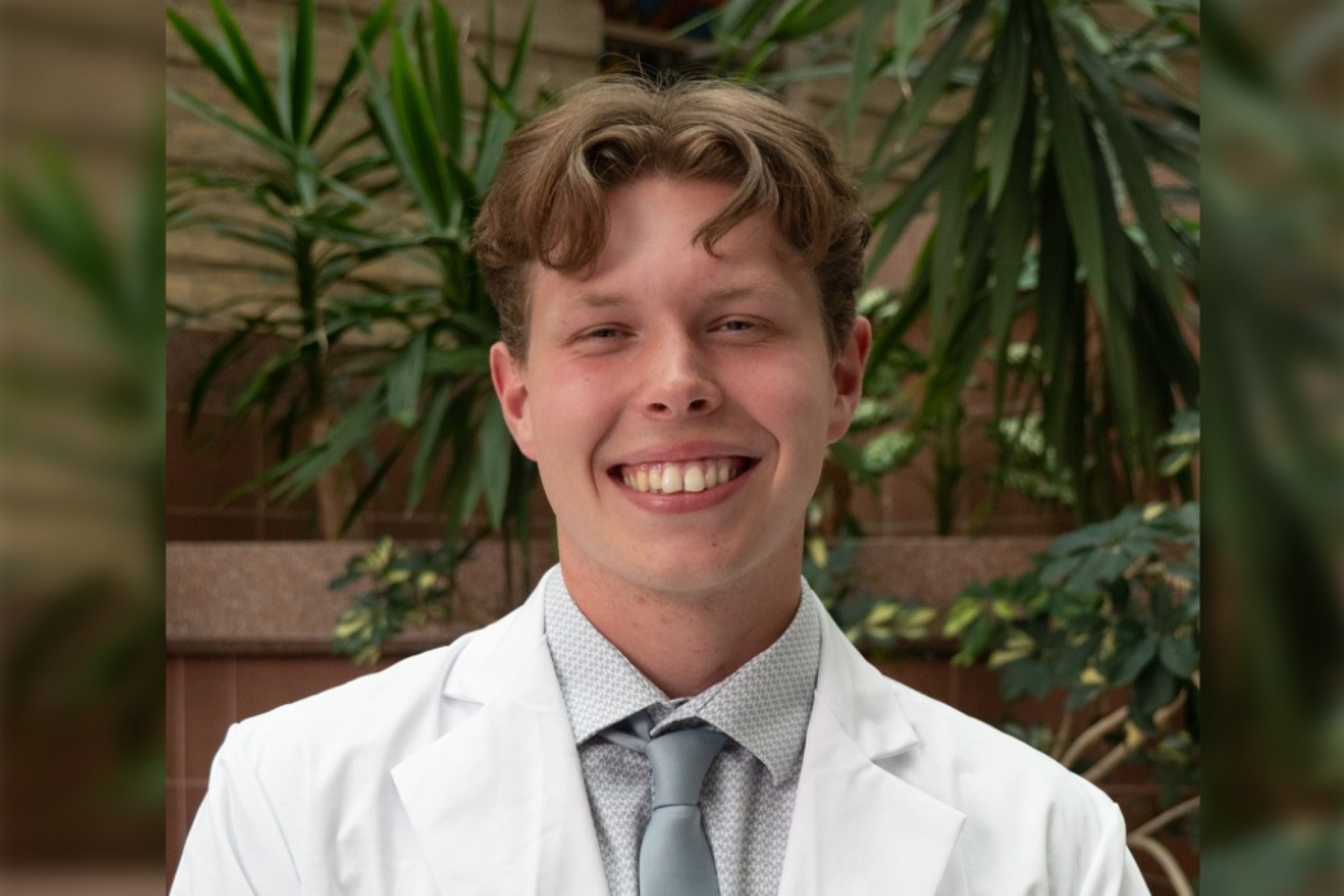 Leif Robak, College of Pharmacy student in white coat smiling at the camera.