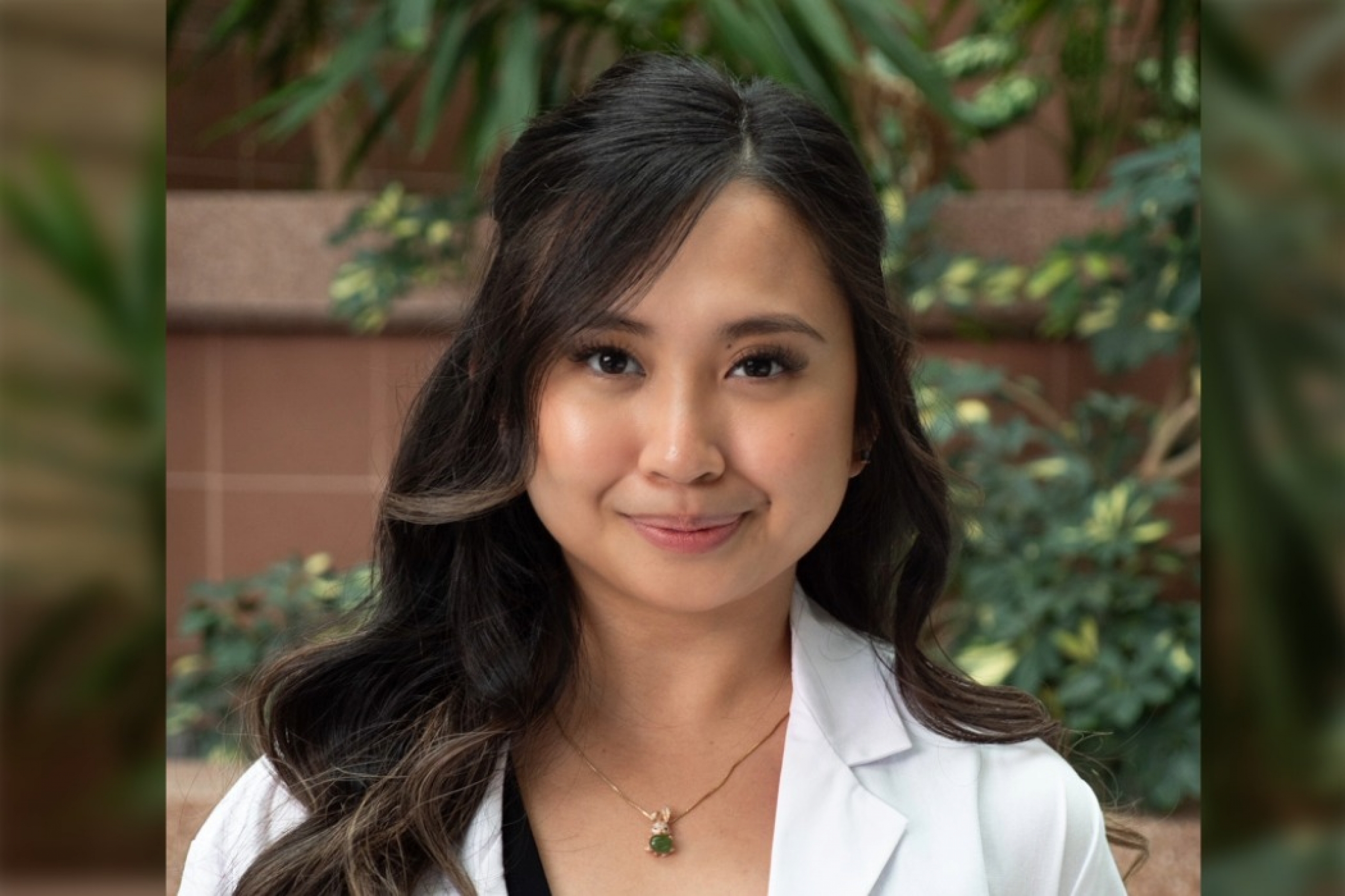 Yves Earielle Pua Robleza, College of Pharmacy student in white coat smiling at the camera while holding a bouquet of flowers.