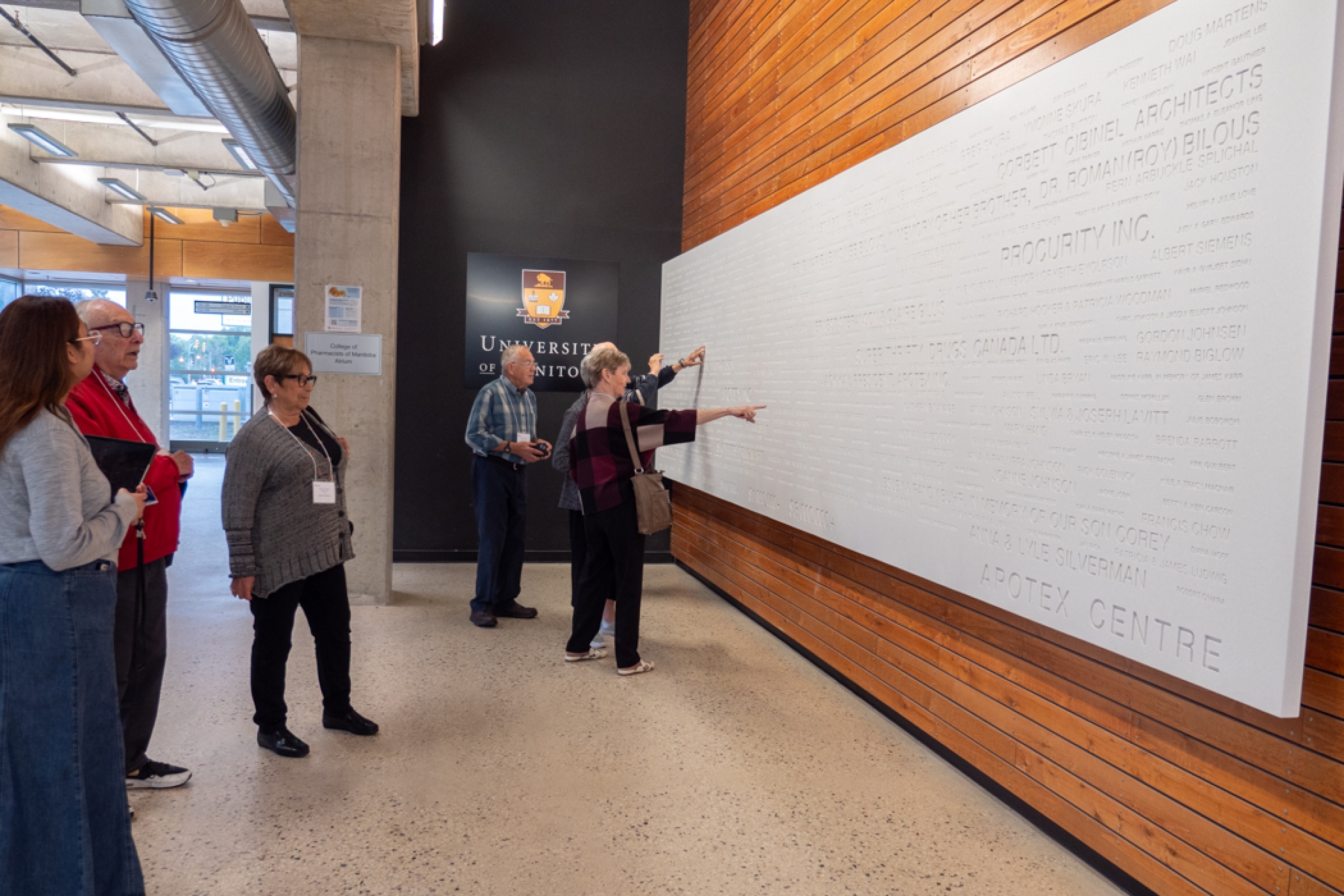 Alumni look at the donor wall at the College of Pharmacy's Apotex building. 