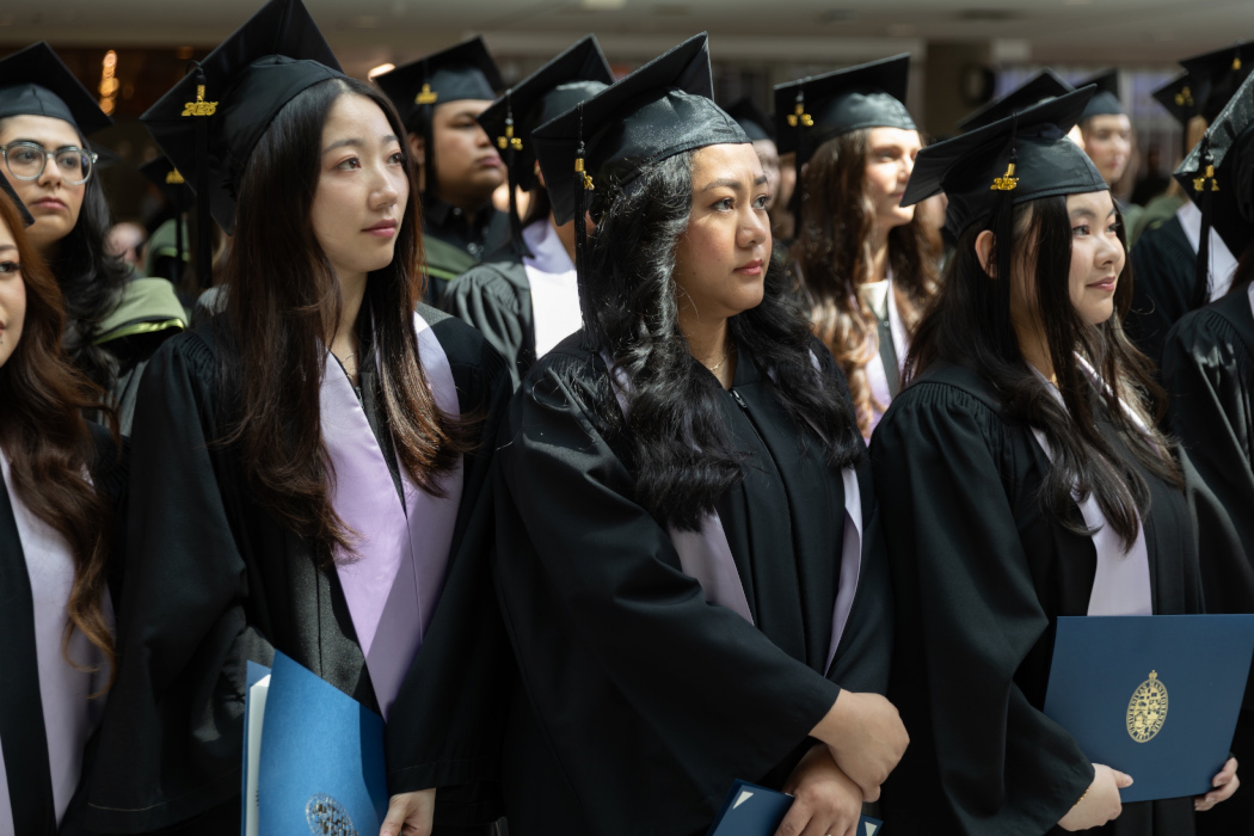 Three rows of students are wearing graduation caps and gowns.
