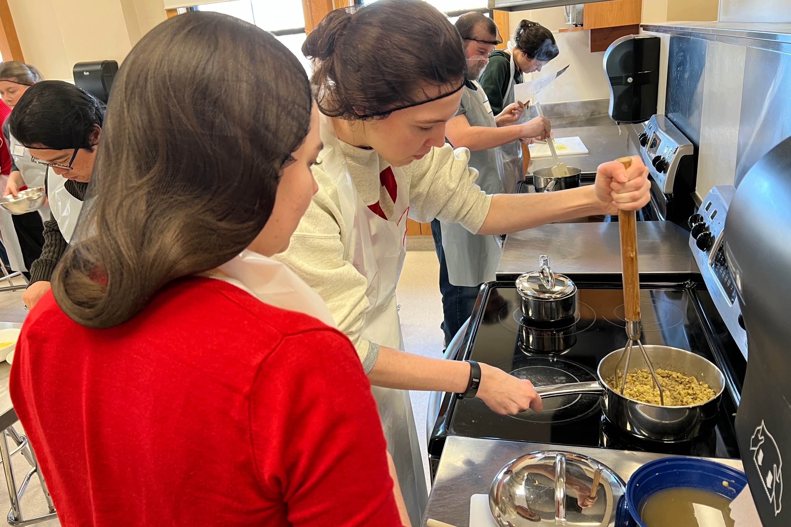Two people bend over a stove.