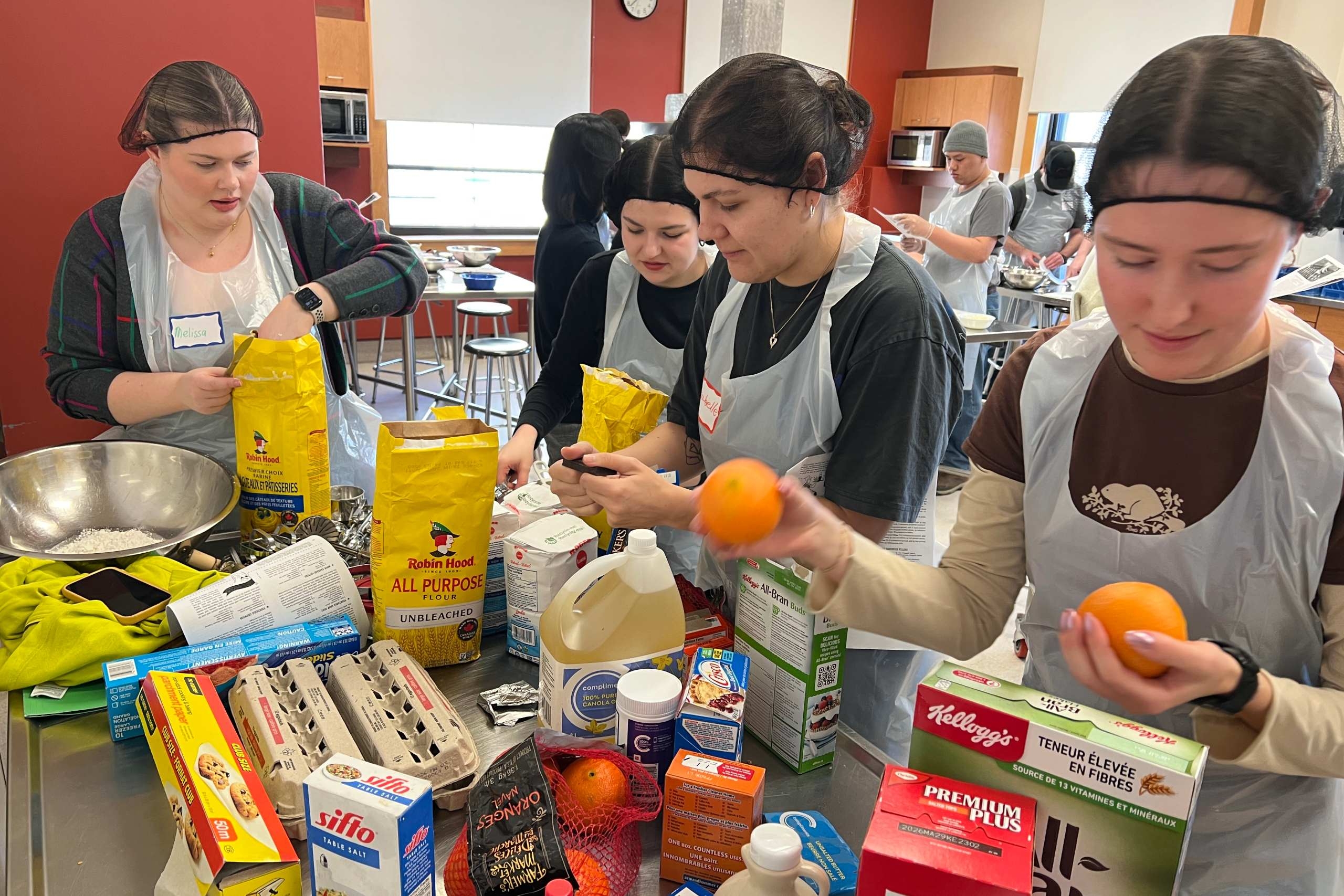 Student gather around a table filled with colourful cooking ingredients.