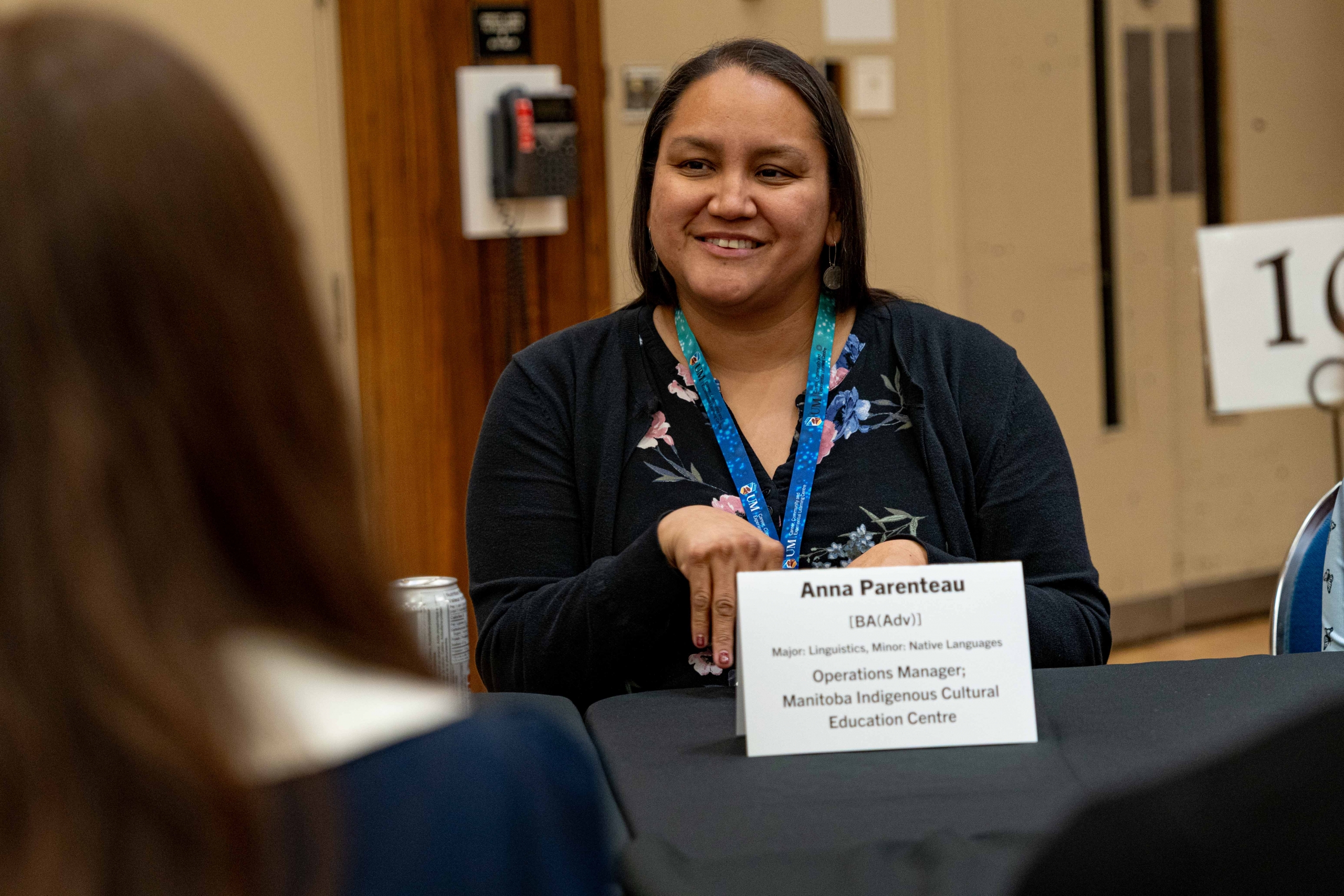 A woman sitting at a table, smiling.