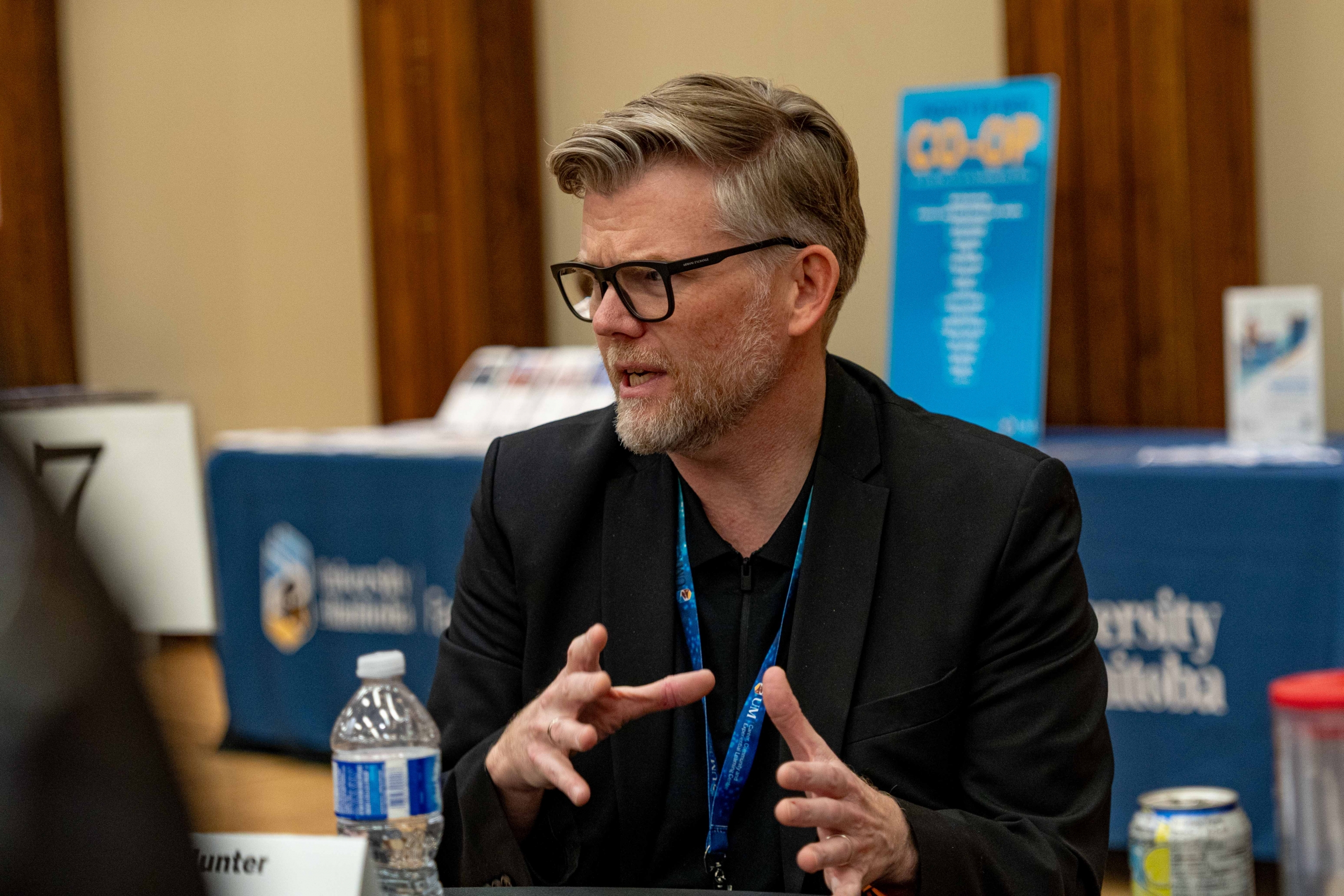 A man sitting at a table, moving his hands while talking.