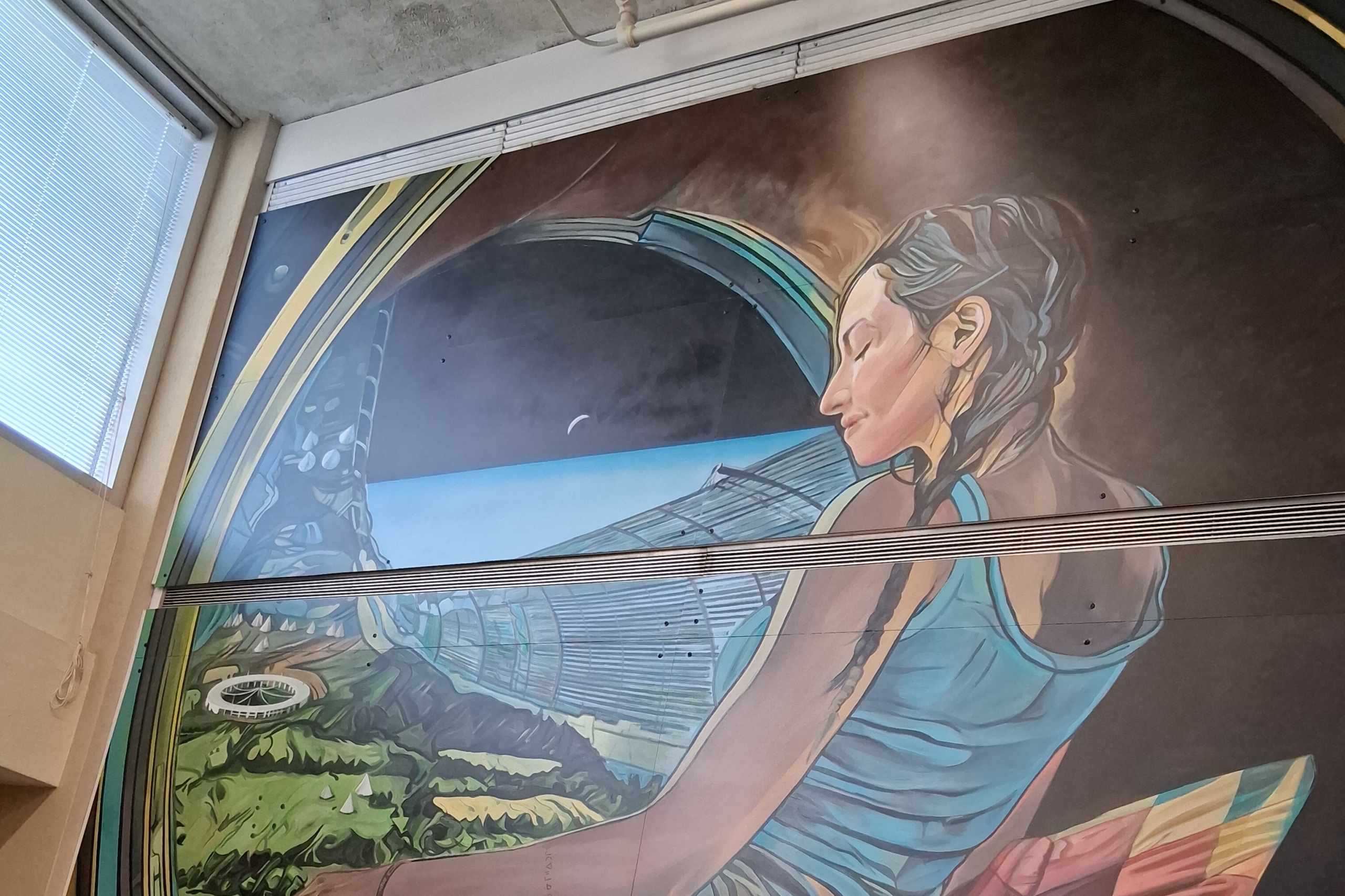 Mural of Indigenous woman in a circle looking down at Earth