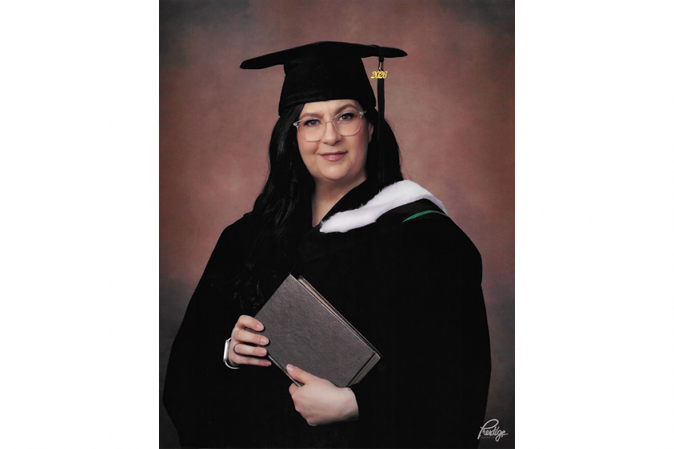 Deanna Jones in a graduation photo wearing a cap and gown and holding a parchment.