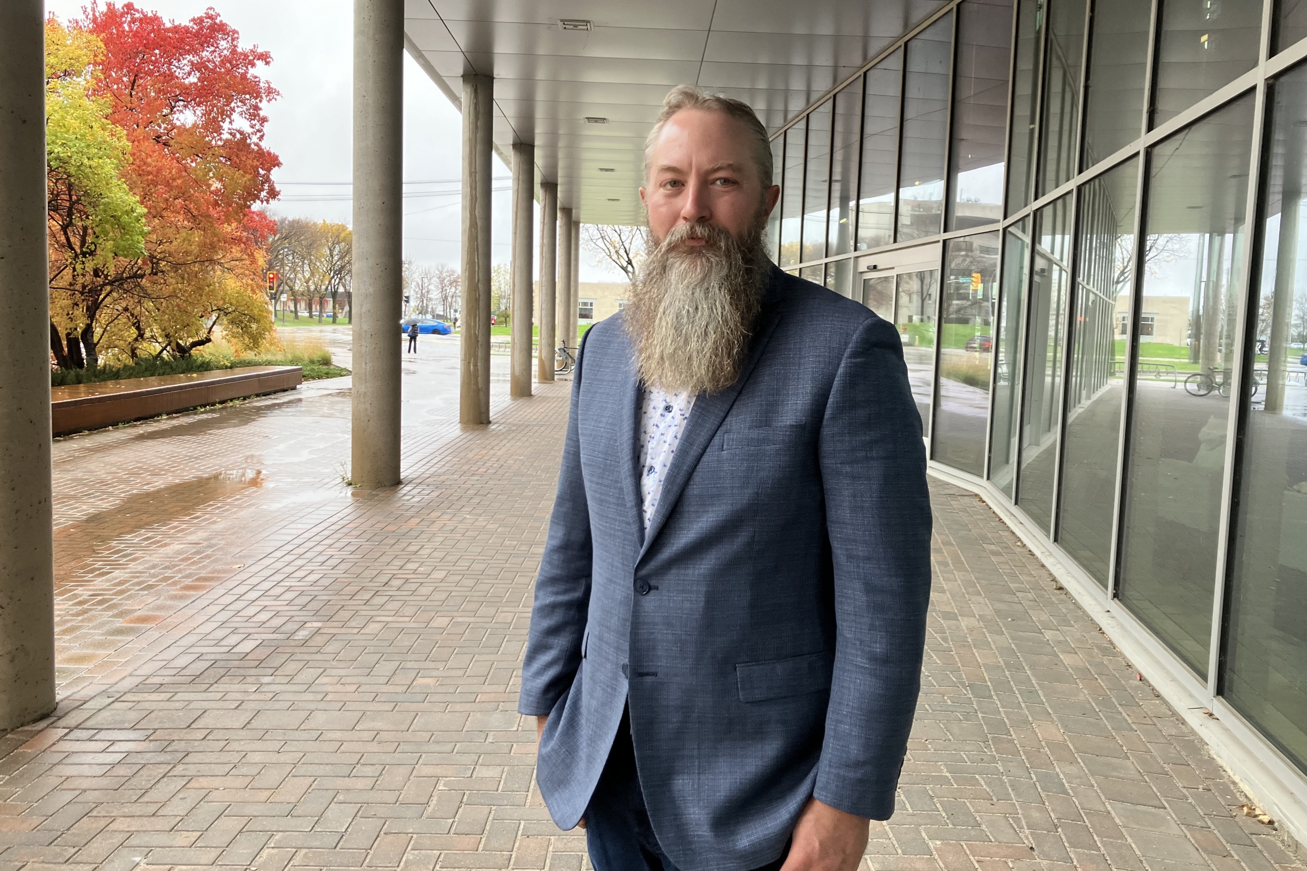 Man with beard stands outside building