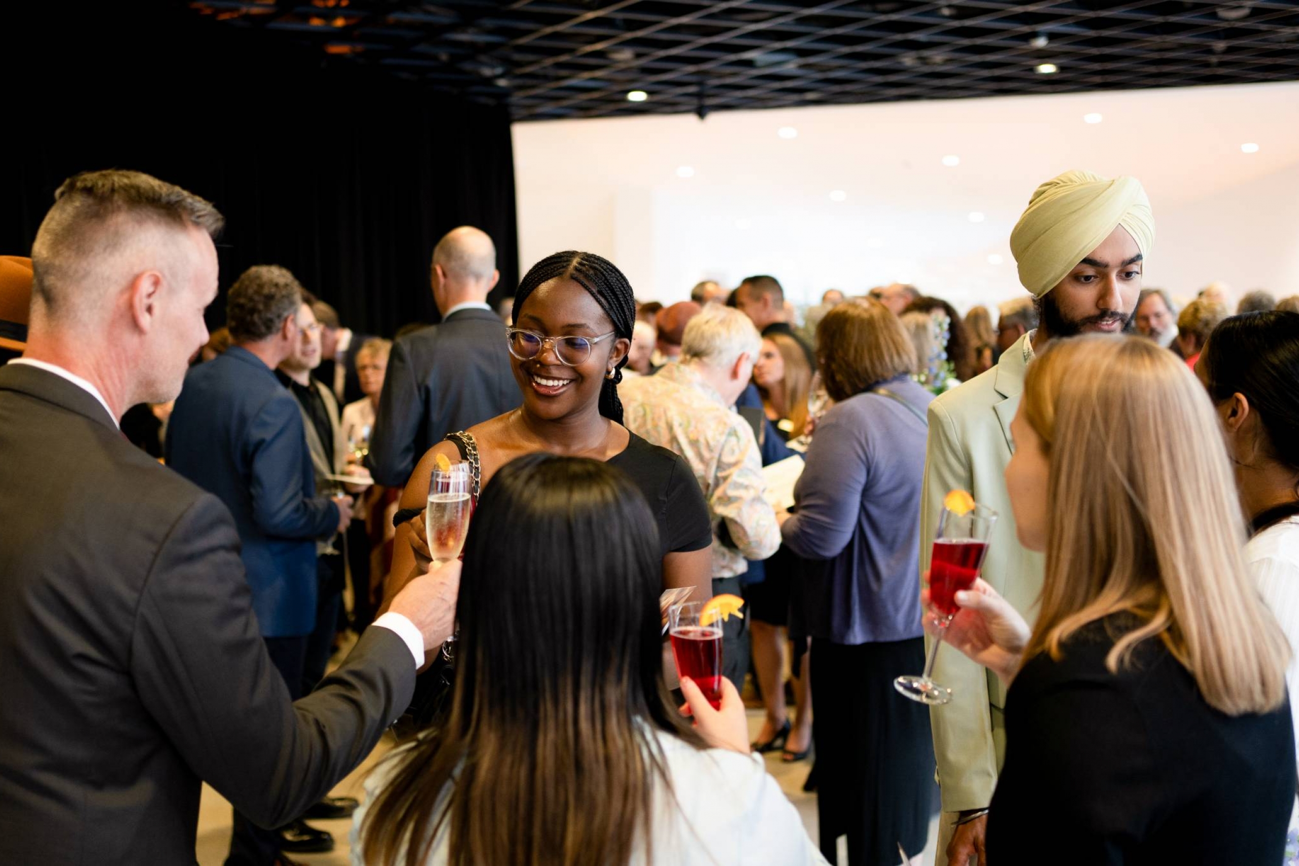A crowd laughing and cheersing drinks