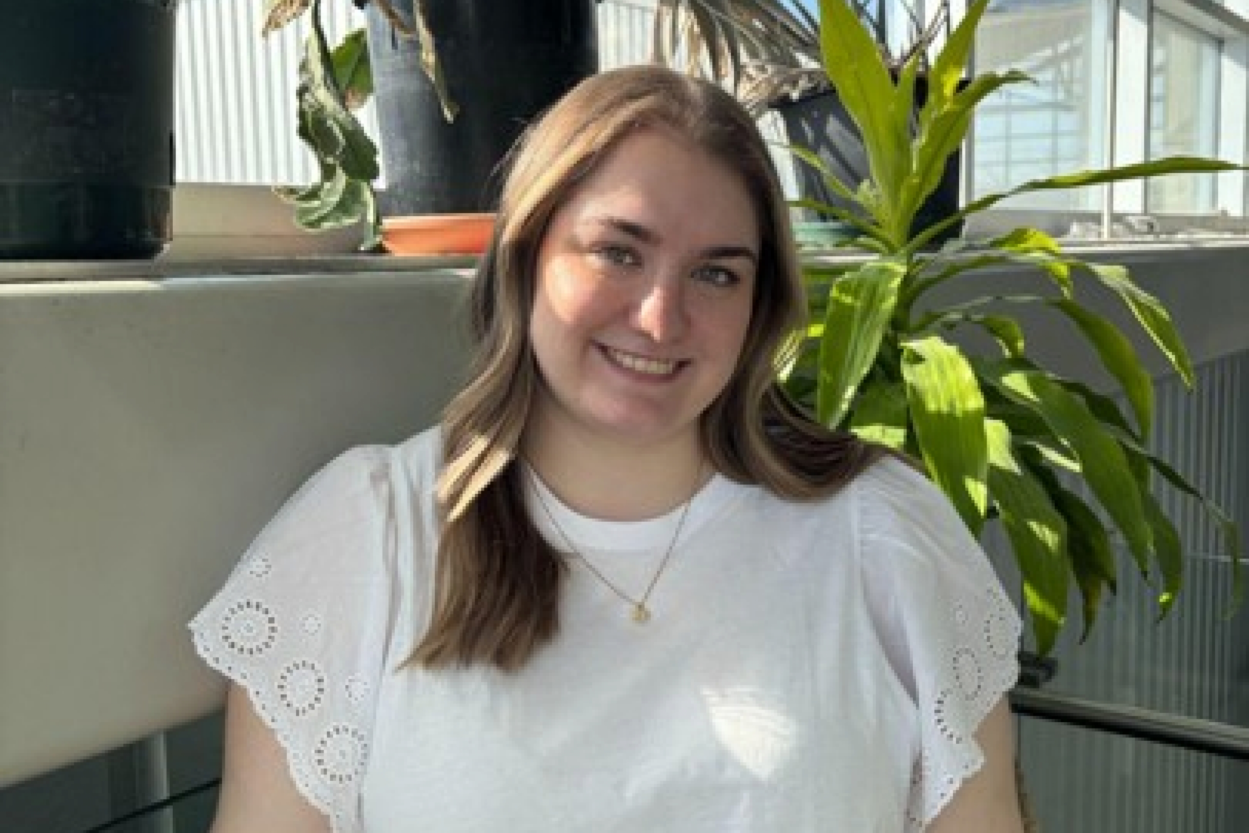 Person posing in front of plants by window