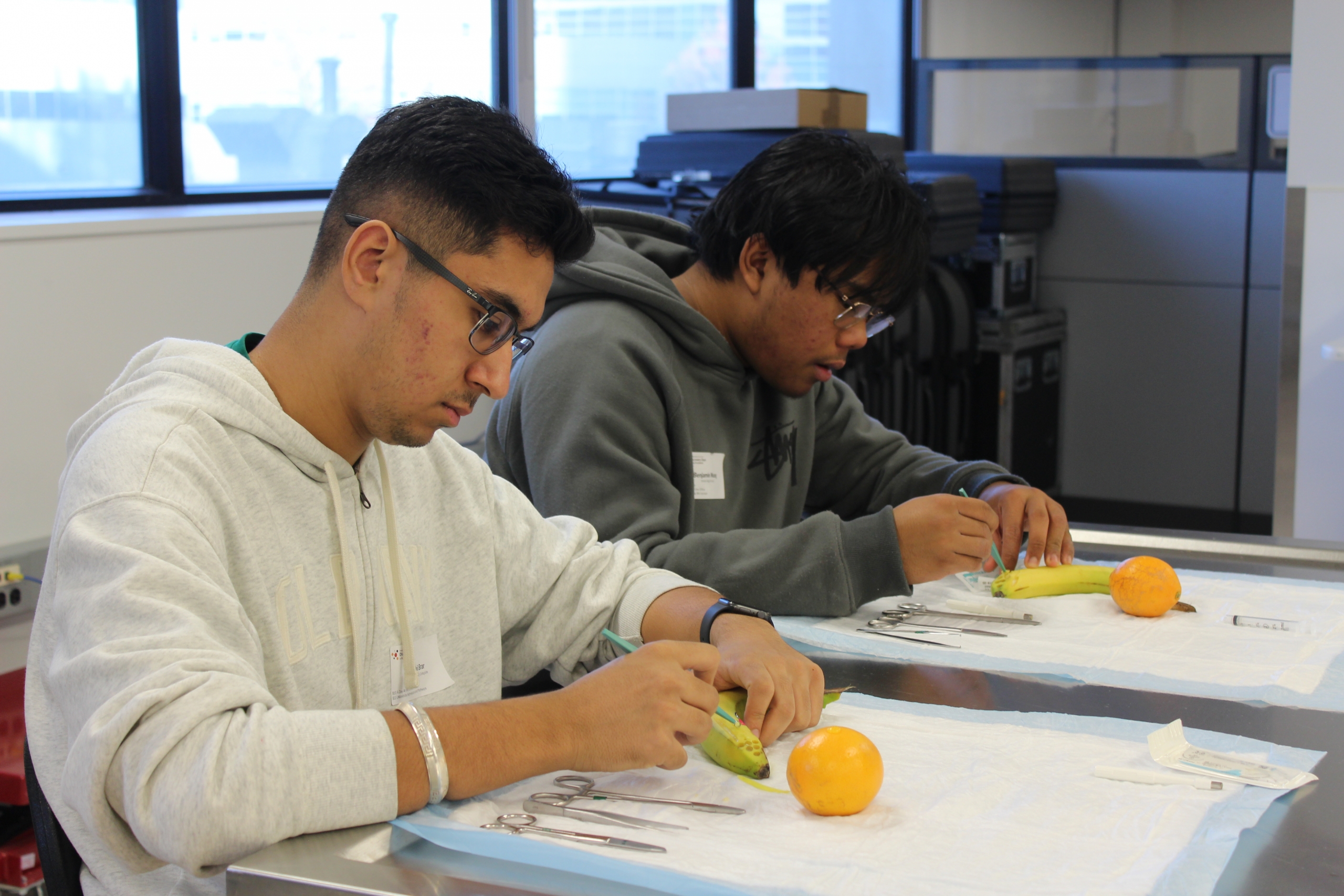 Harsahij Brar holds a medical instrument against a banana.