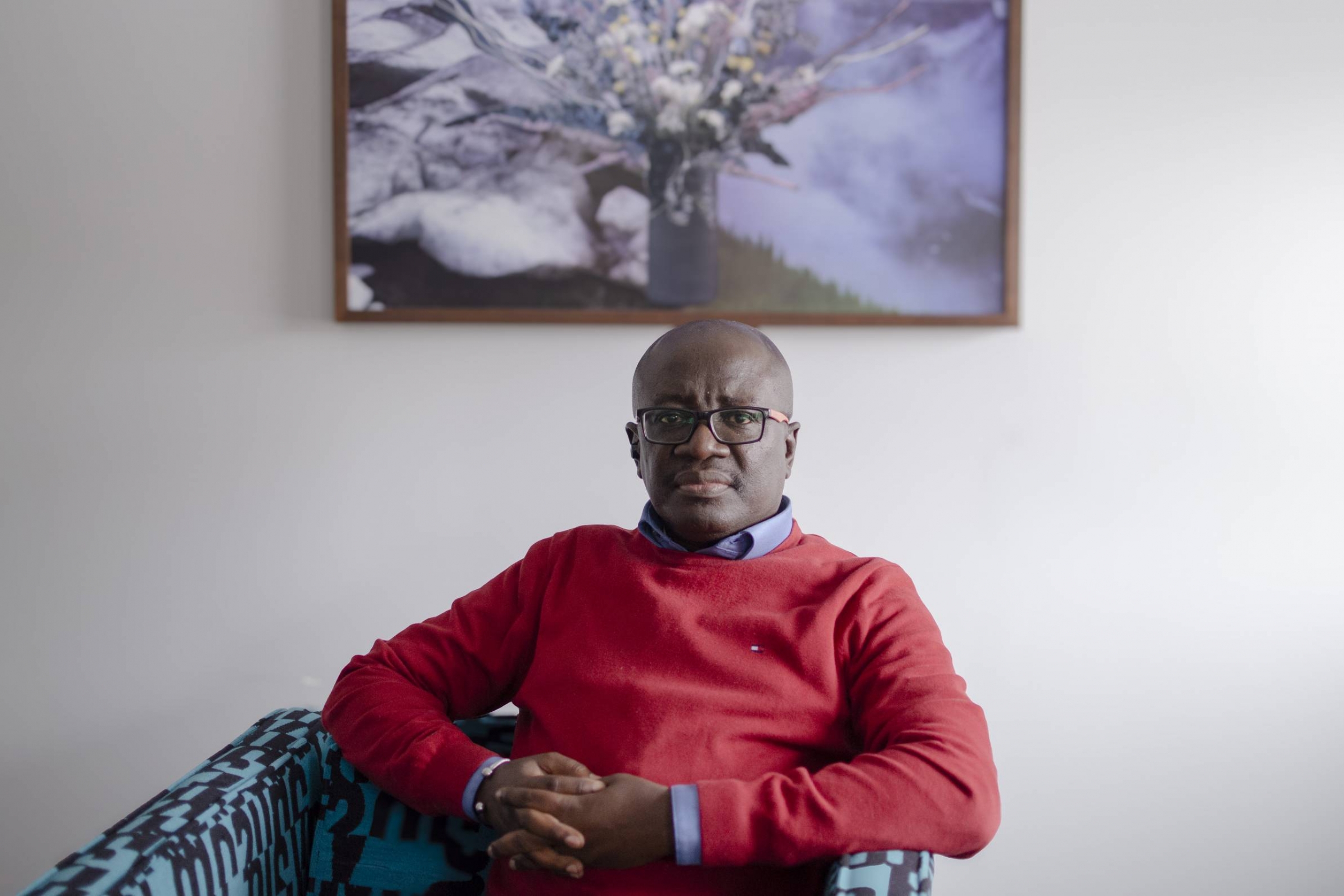 Edmund Opoku-Agyeman sitting in a chair wearing a red crewneck