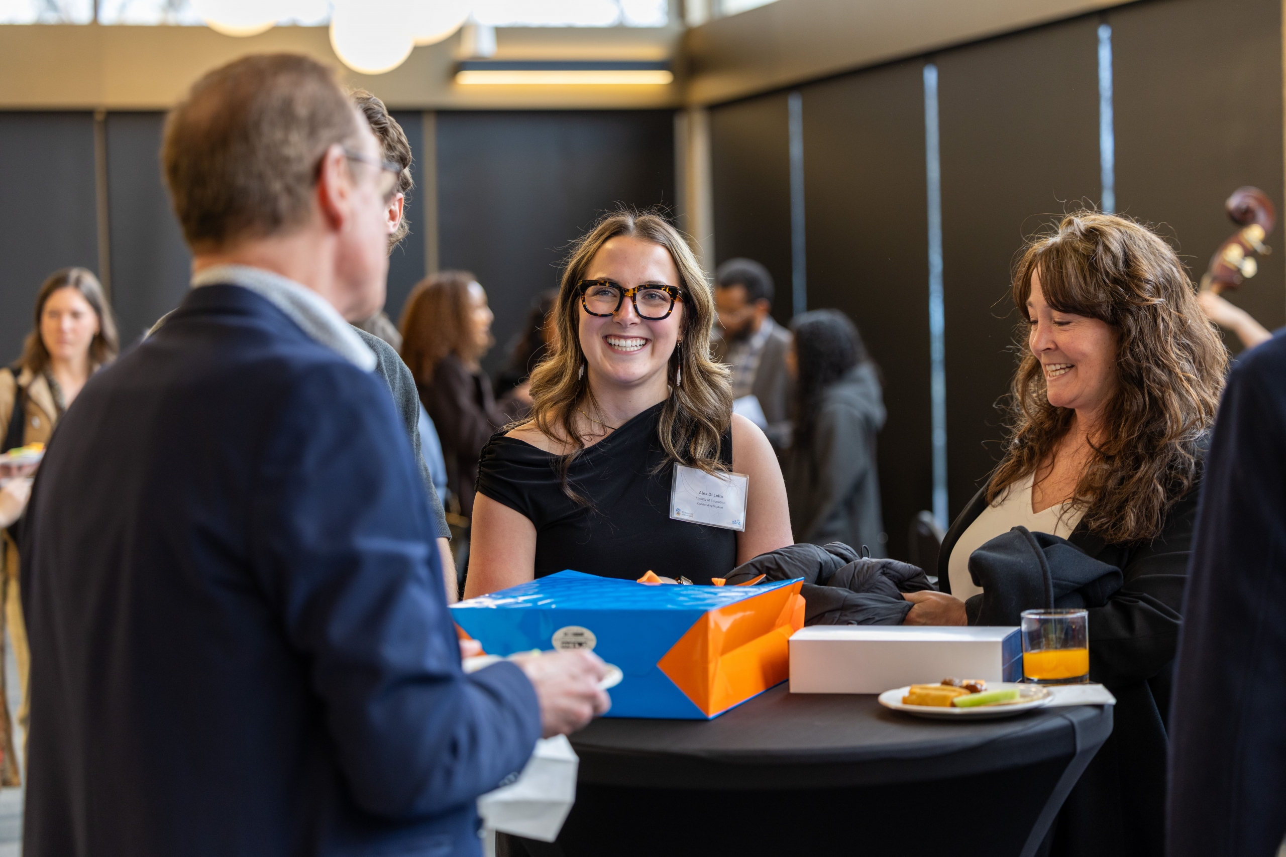A group of attendees are enjoying pleasant conversation with refreshments at the end of the reception.