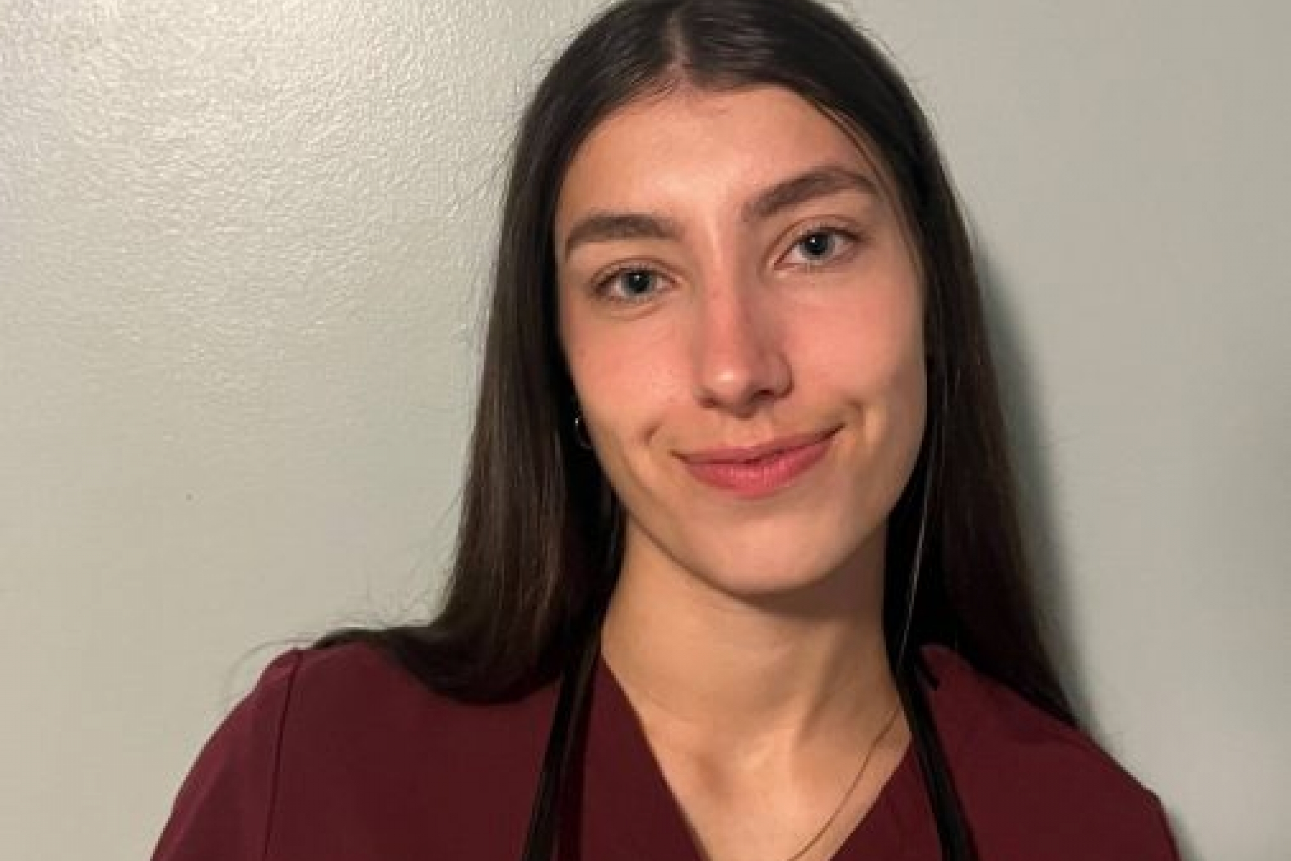 Emily Firth wearing scrubs, holding a stethoscope around her neck.