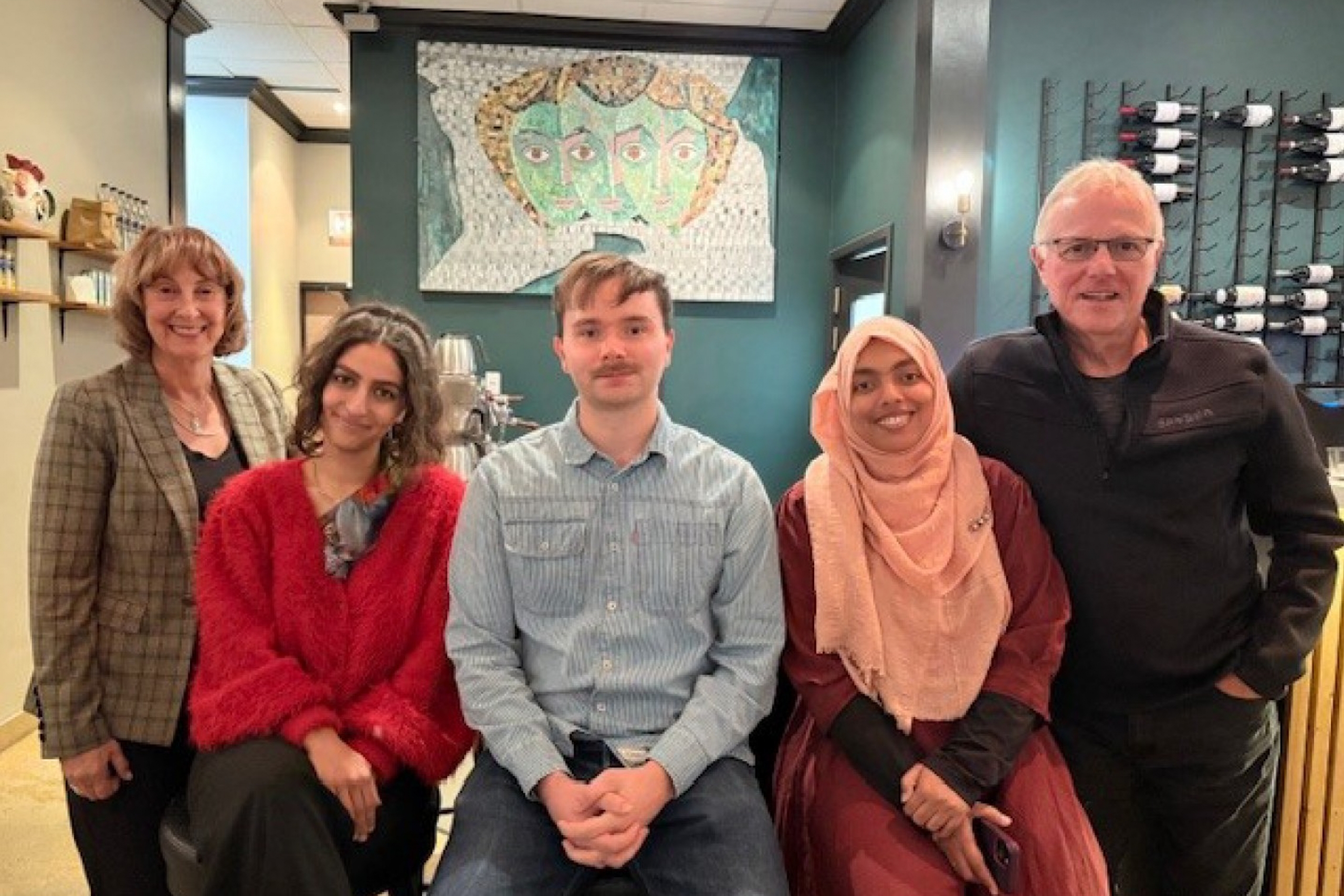A diverse group of five people smiling.