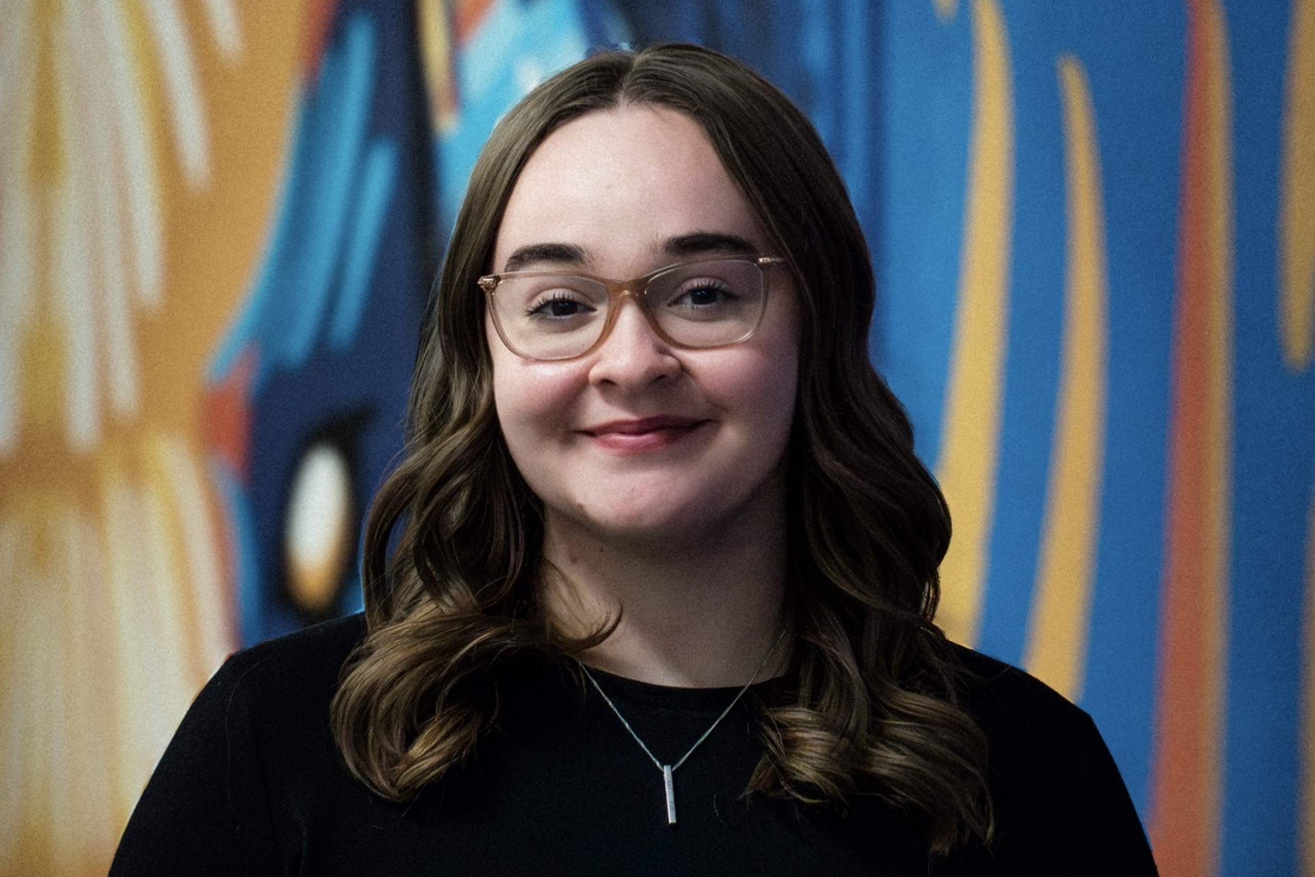 Naomi Husdon poses for a headshot with a bison mural in the background.