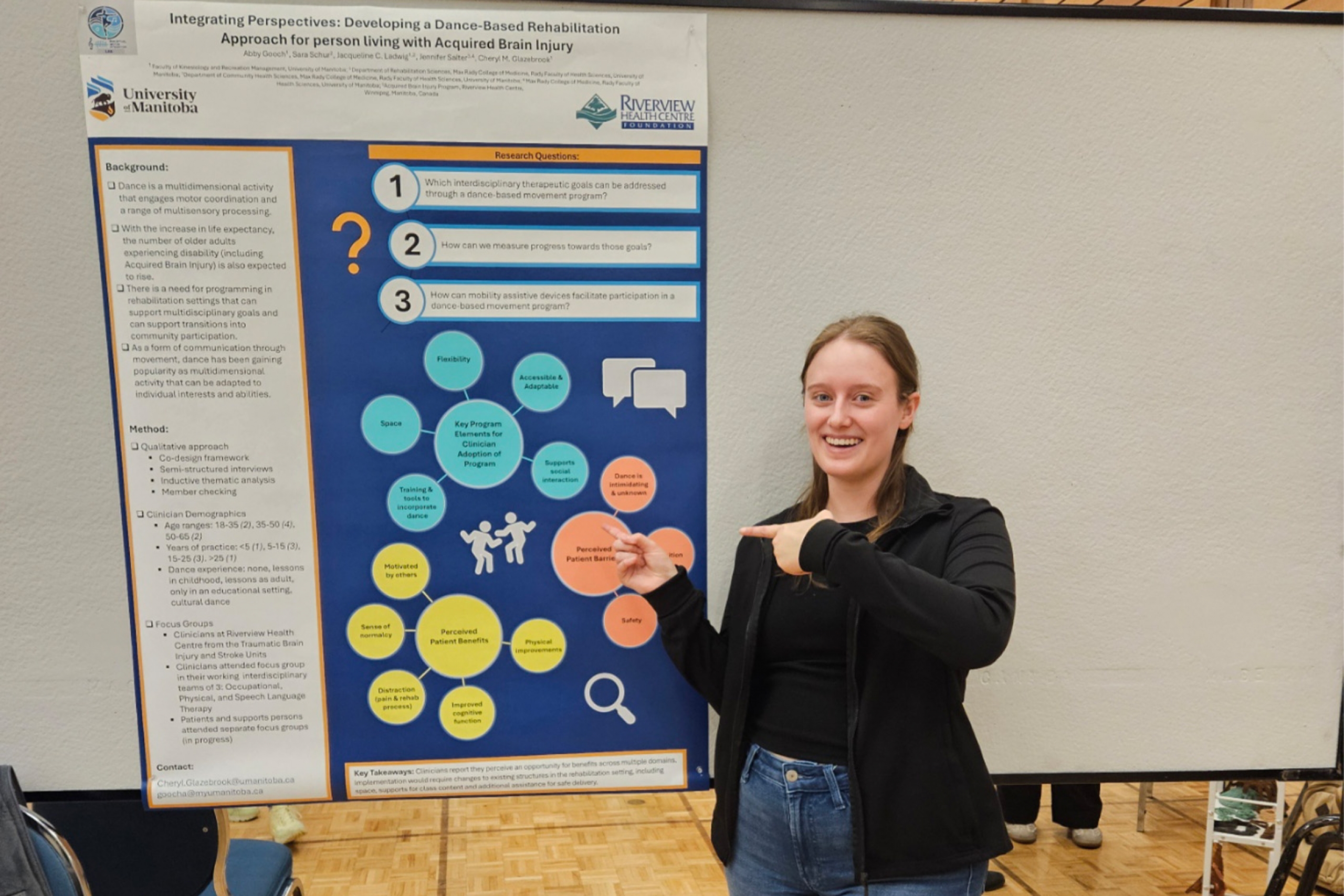 Abby Gooch smiling and pointing a her research poster