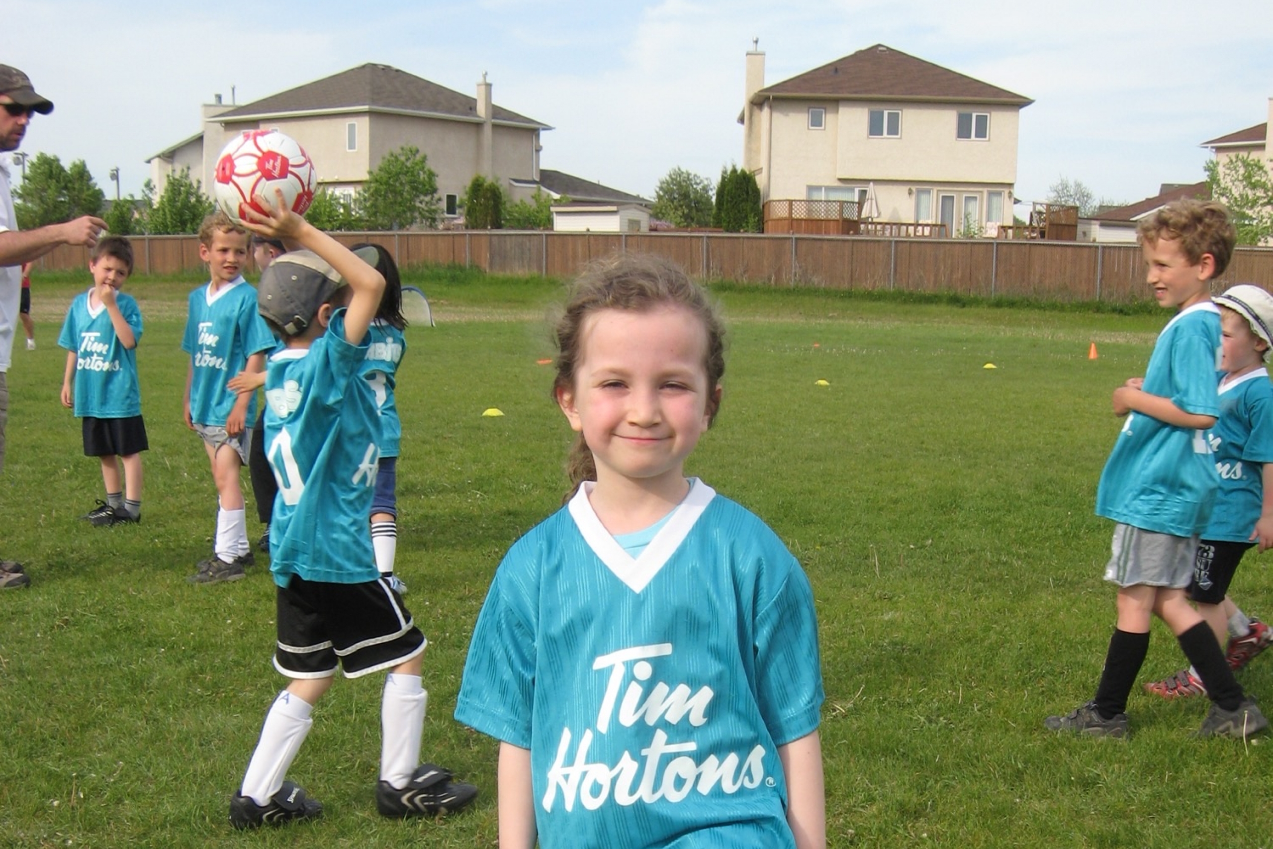 A young girl poses with her foot on a soccer ball.