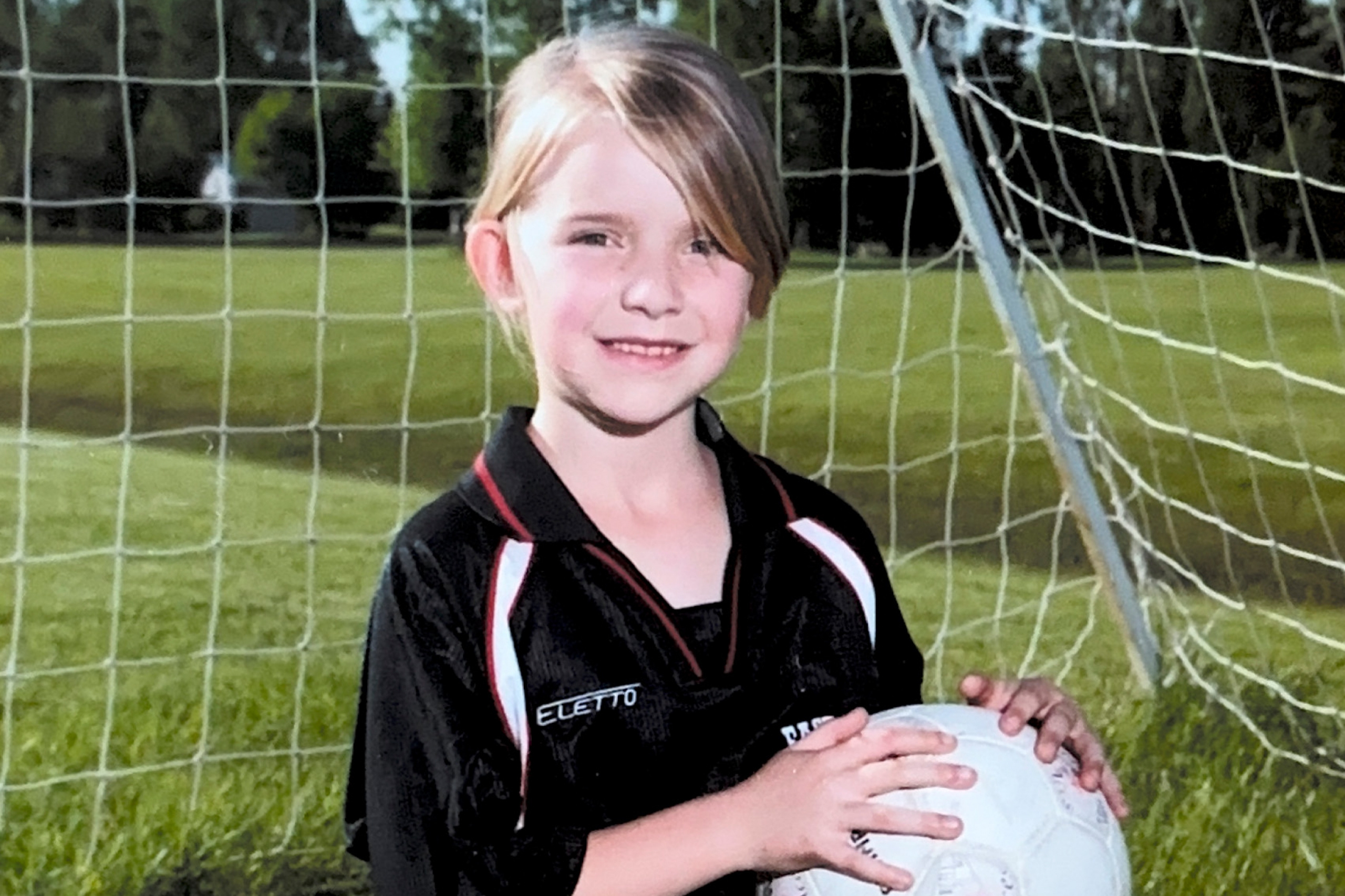 Kaitlyn Klassen as a young girl posing with a soccer ball for a team photo