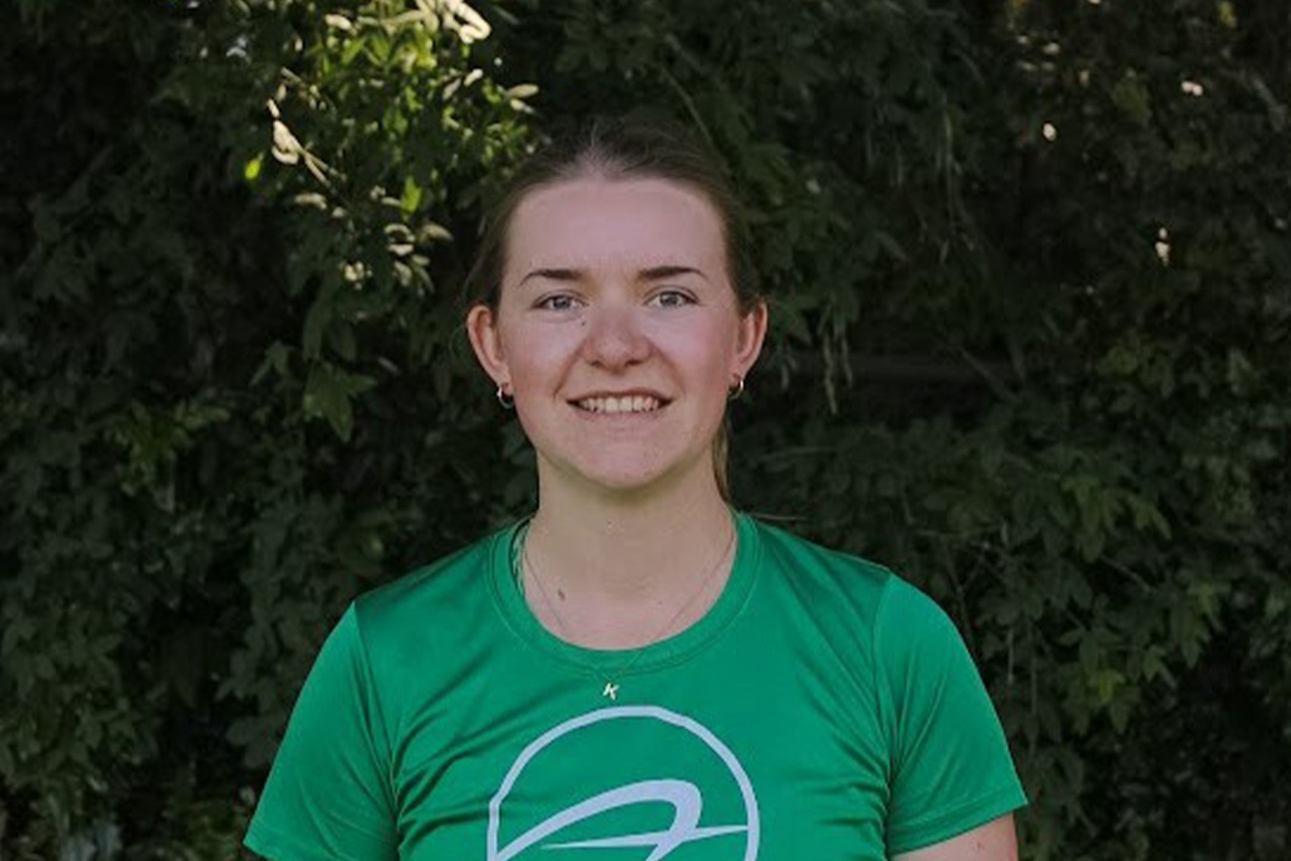 Kaitlyn Klassen standing in front of greenery smiling