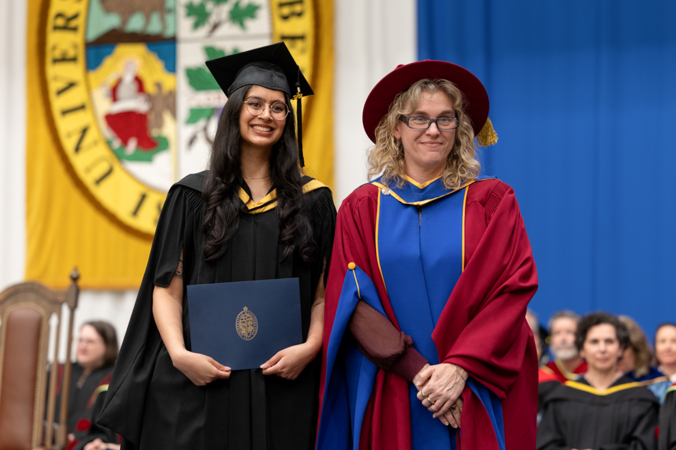 A graduate in robes with another person.