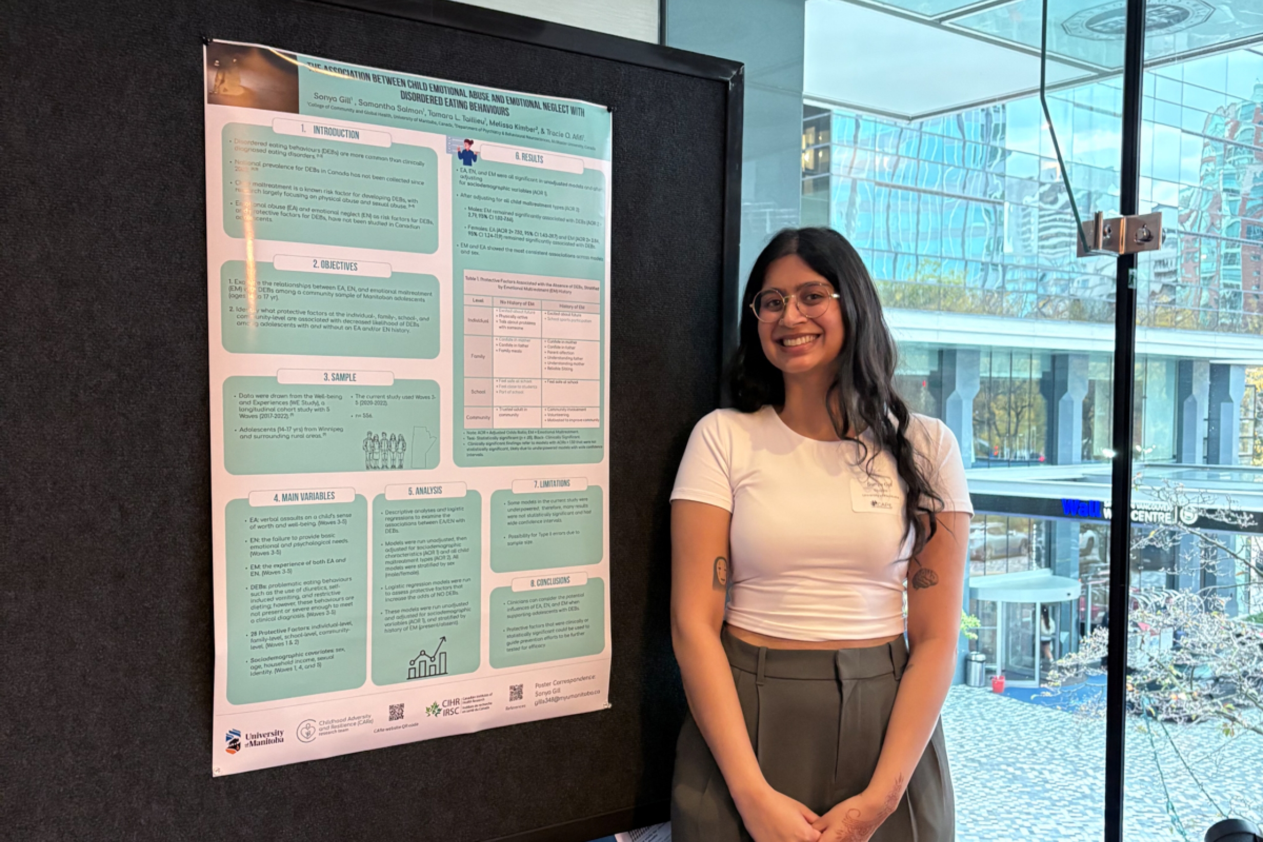 A student smiling in front of a research poster.