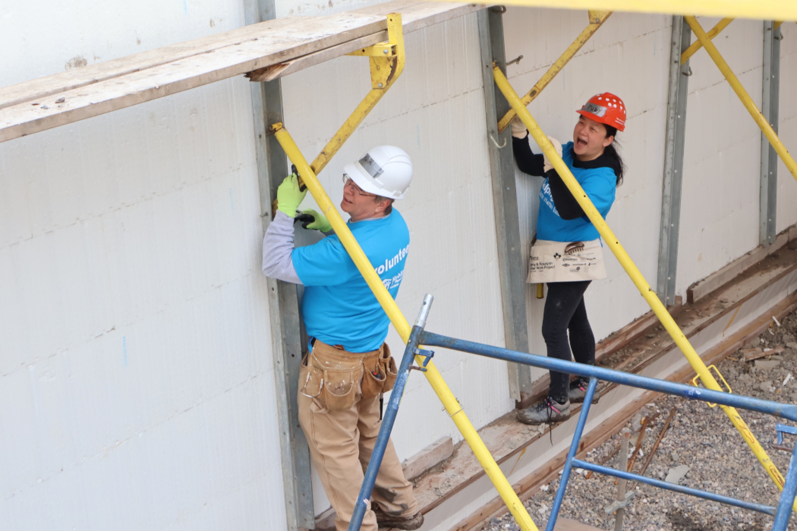 Two people wearing hardhats on a construction site.