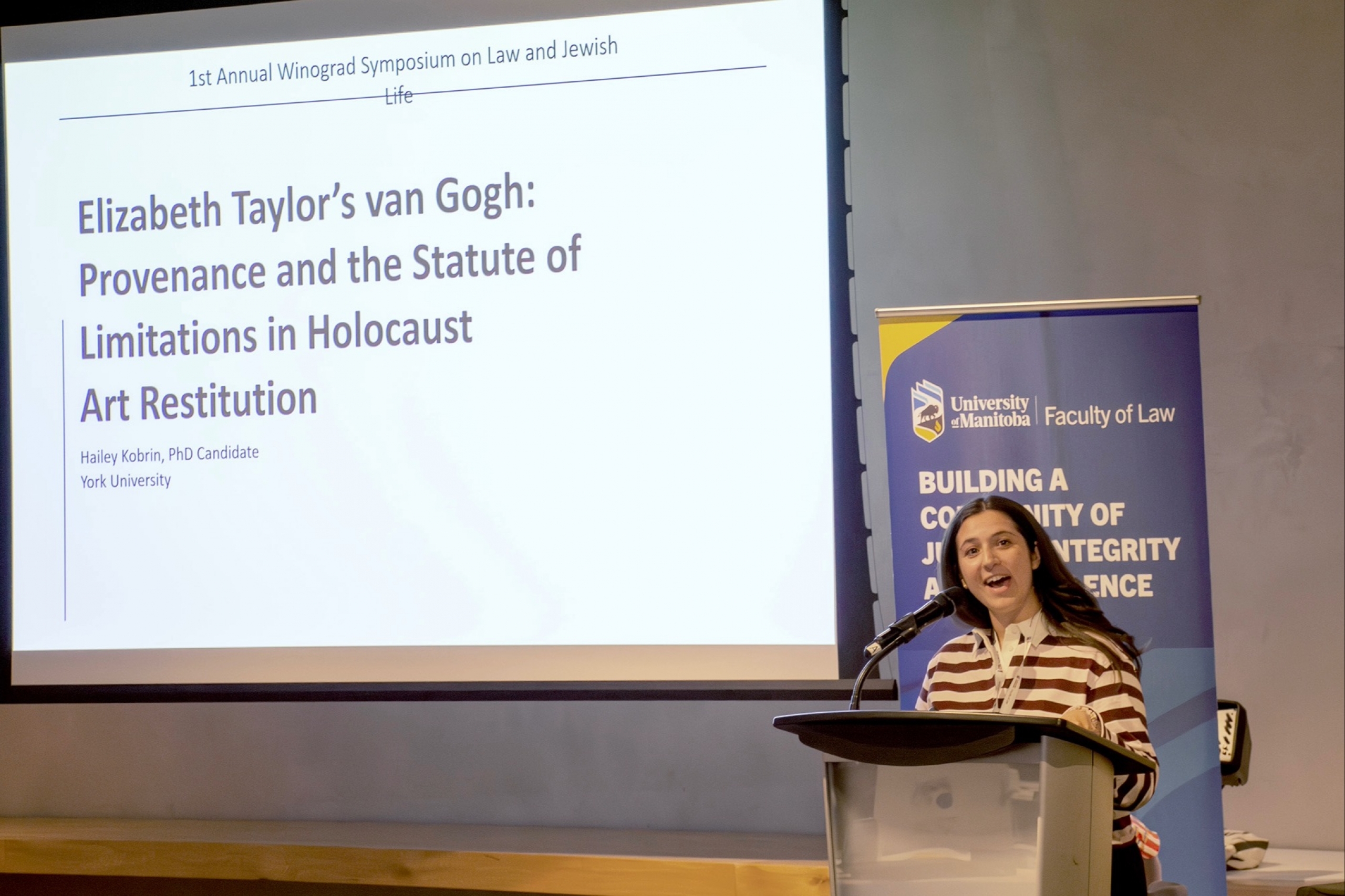 A student gives a presentation in front of a screen standing at a podium