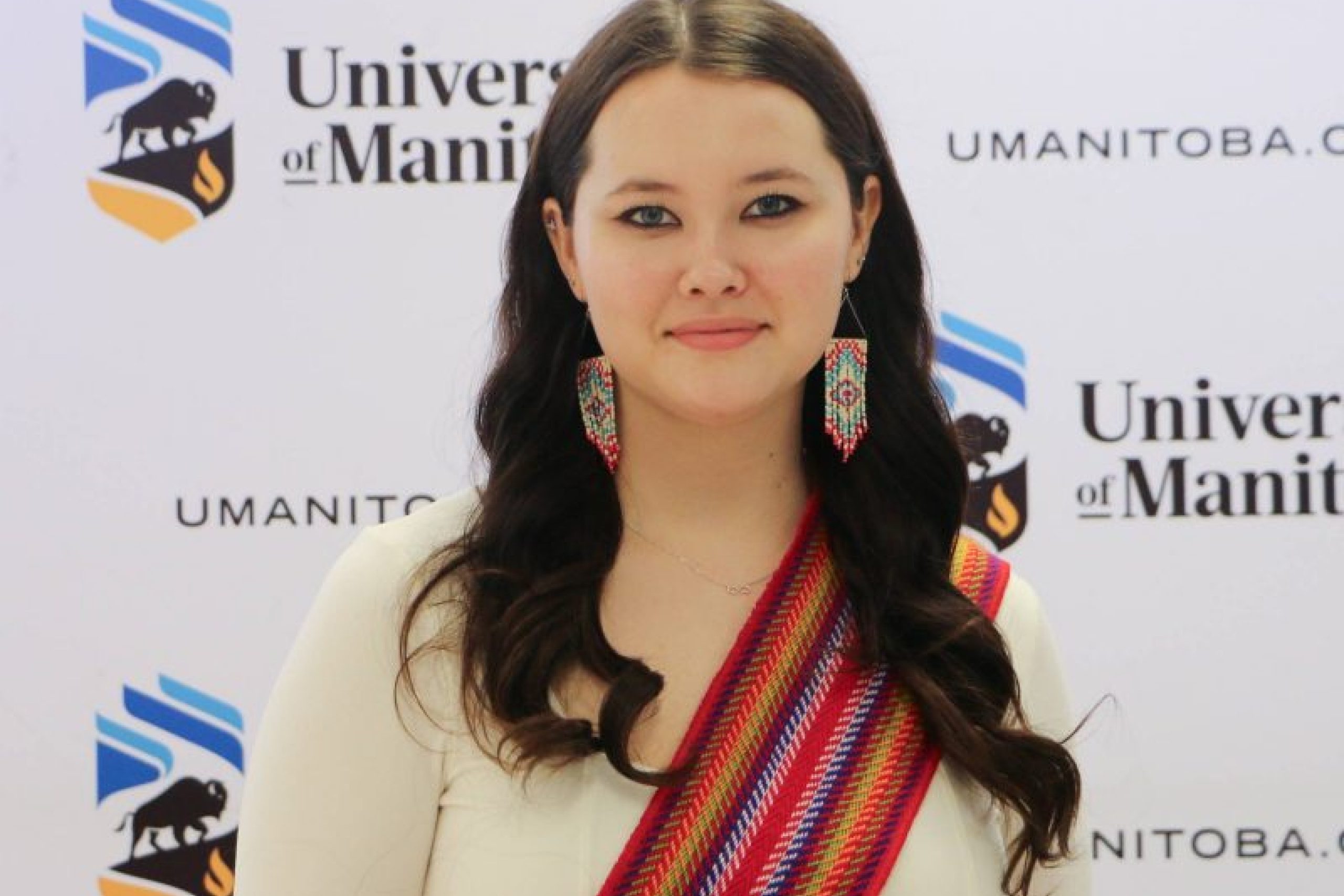 Young smiling woman with brown hair wearing a Metis sash