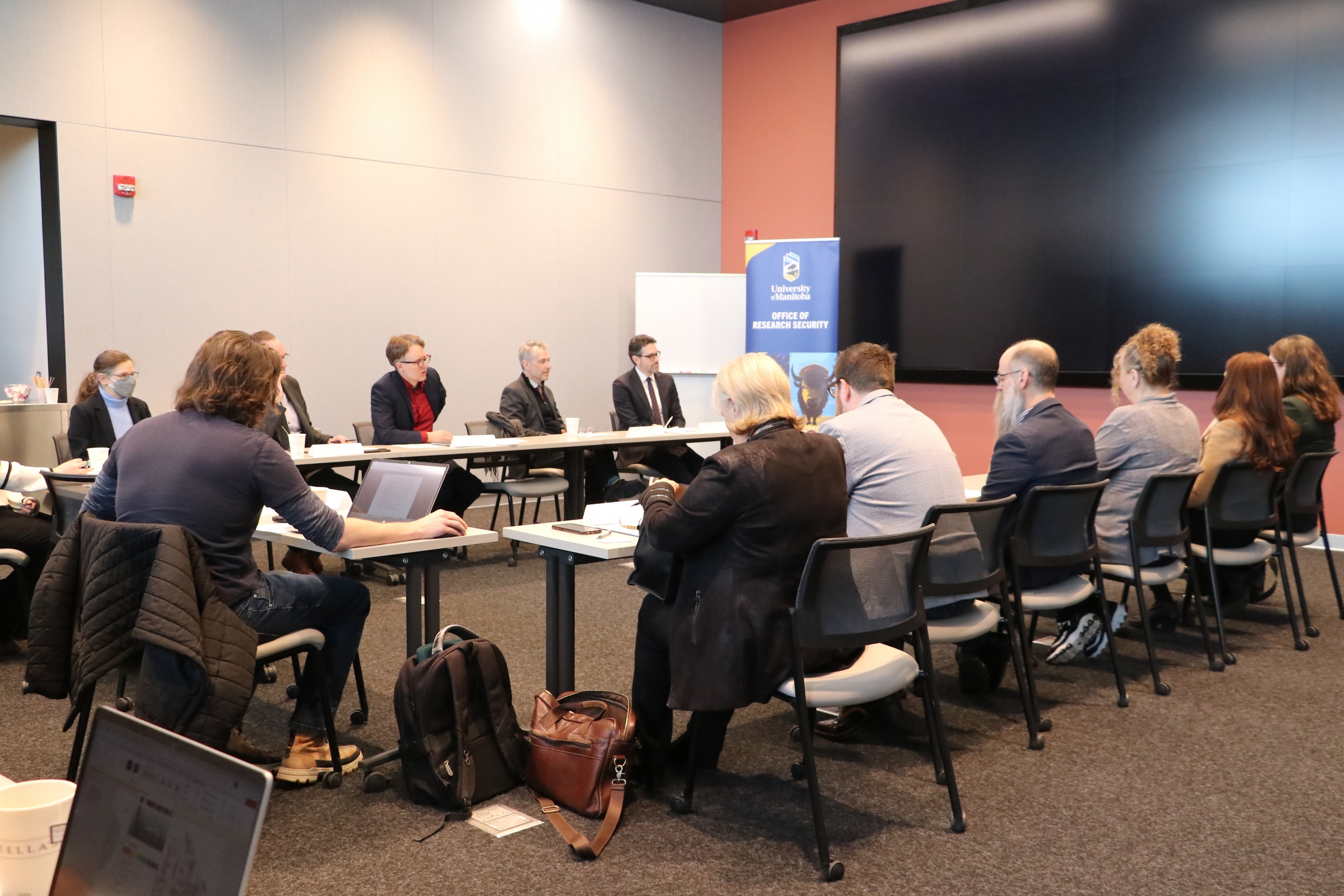 Participants seated around tables engage with a panel during a roundtable discussion.