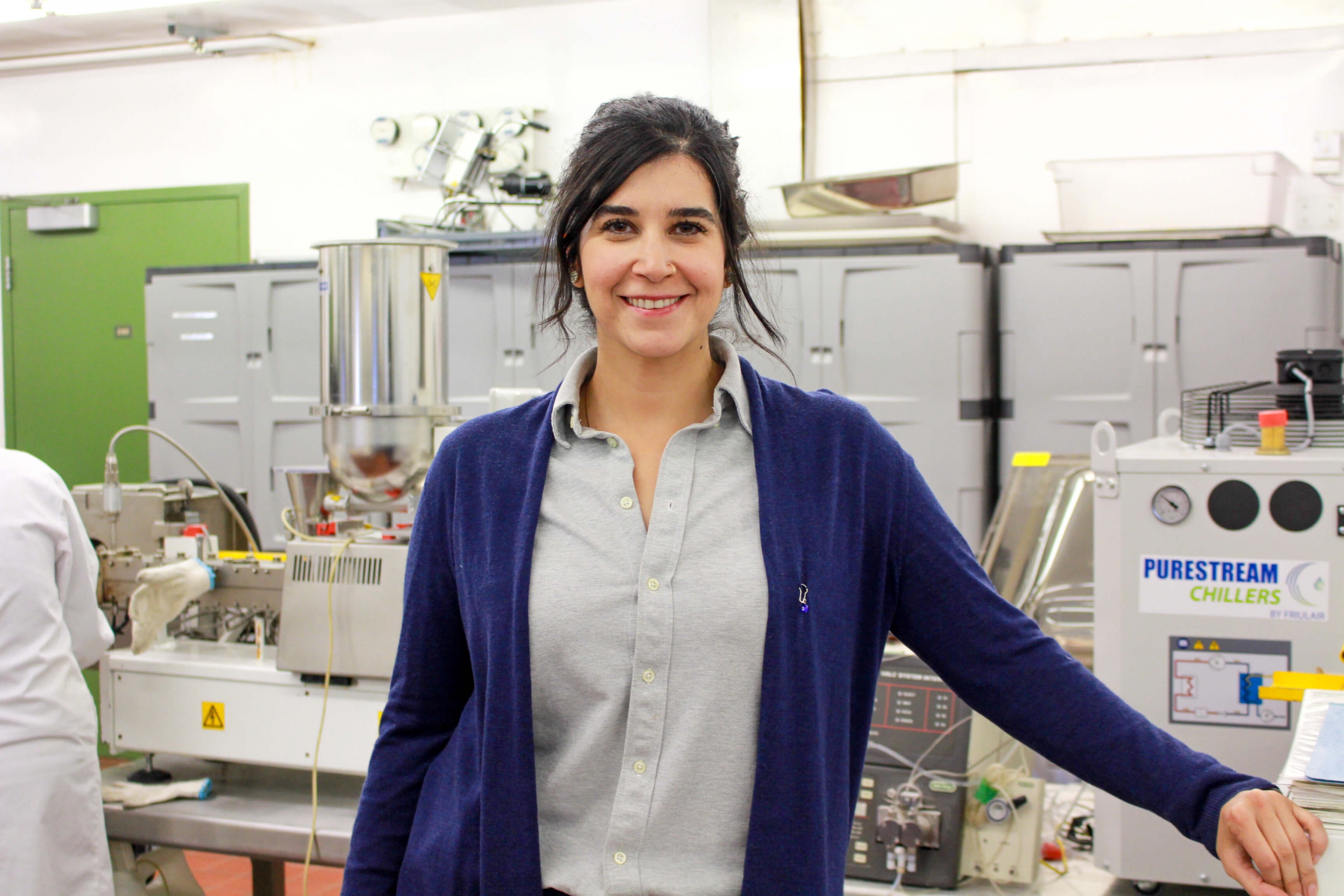 A woman stands in a lab facing the camera