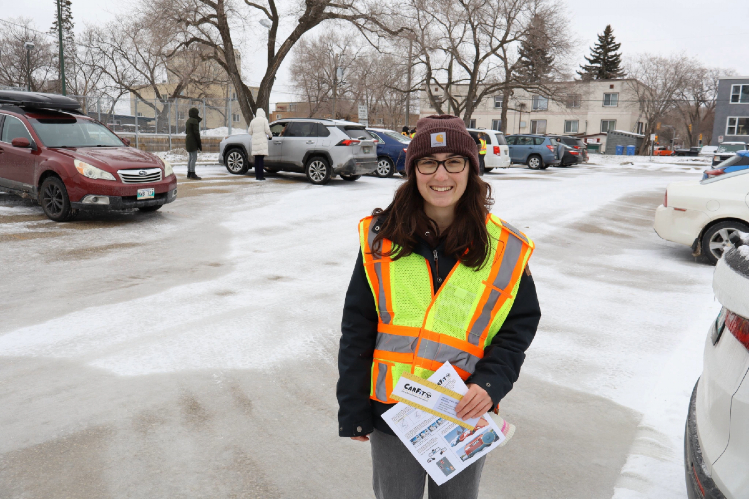 Cassidy Copple stands in a parking lot holding a CarFit ruler and survey.