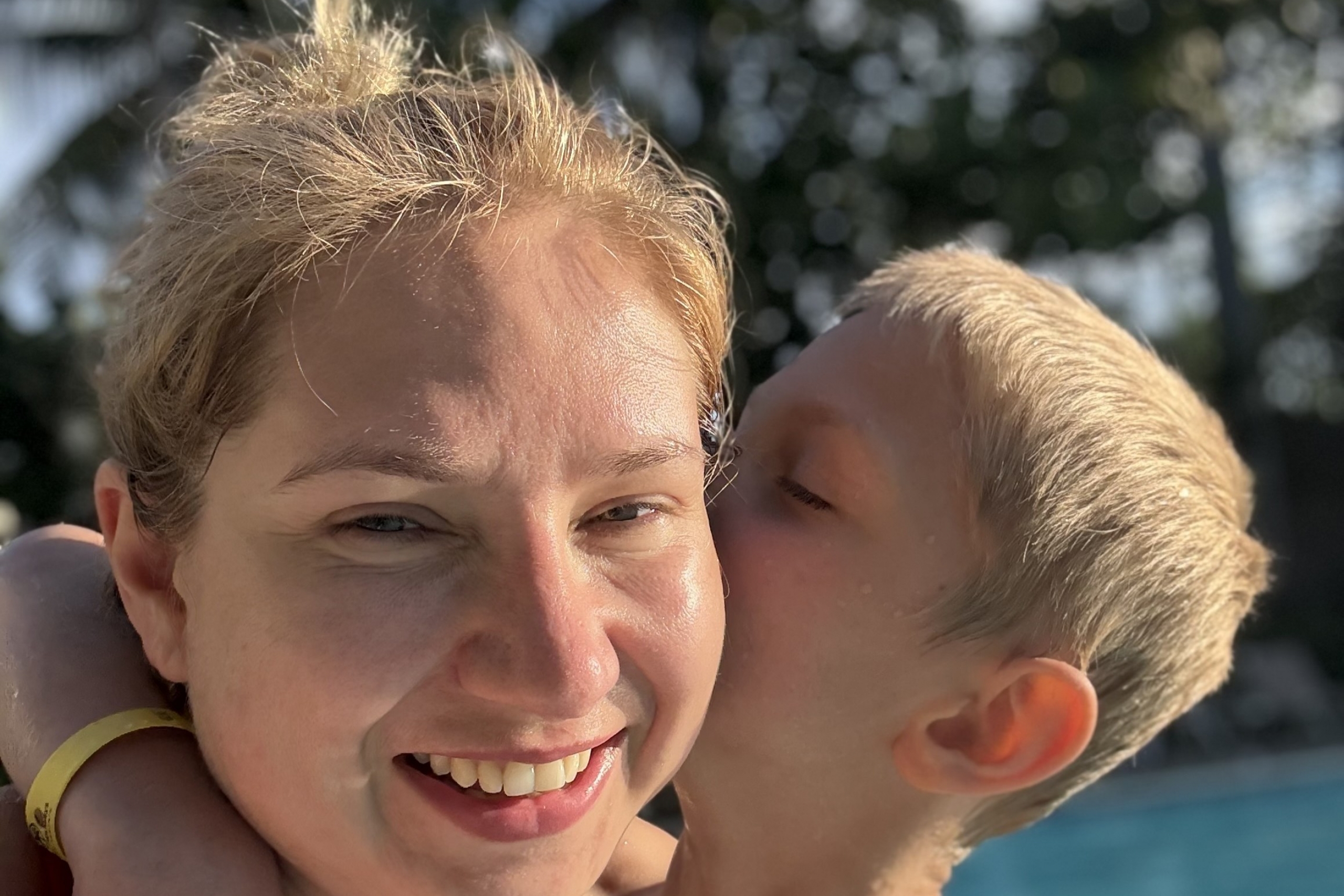a young son kisses his mother on the cheek
