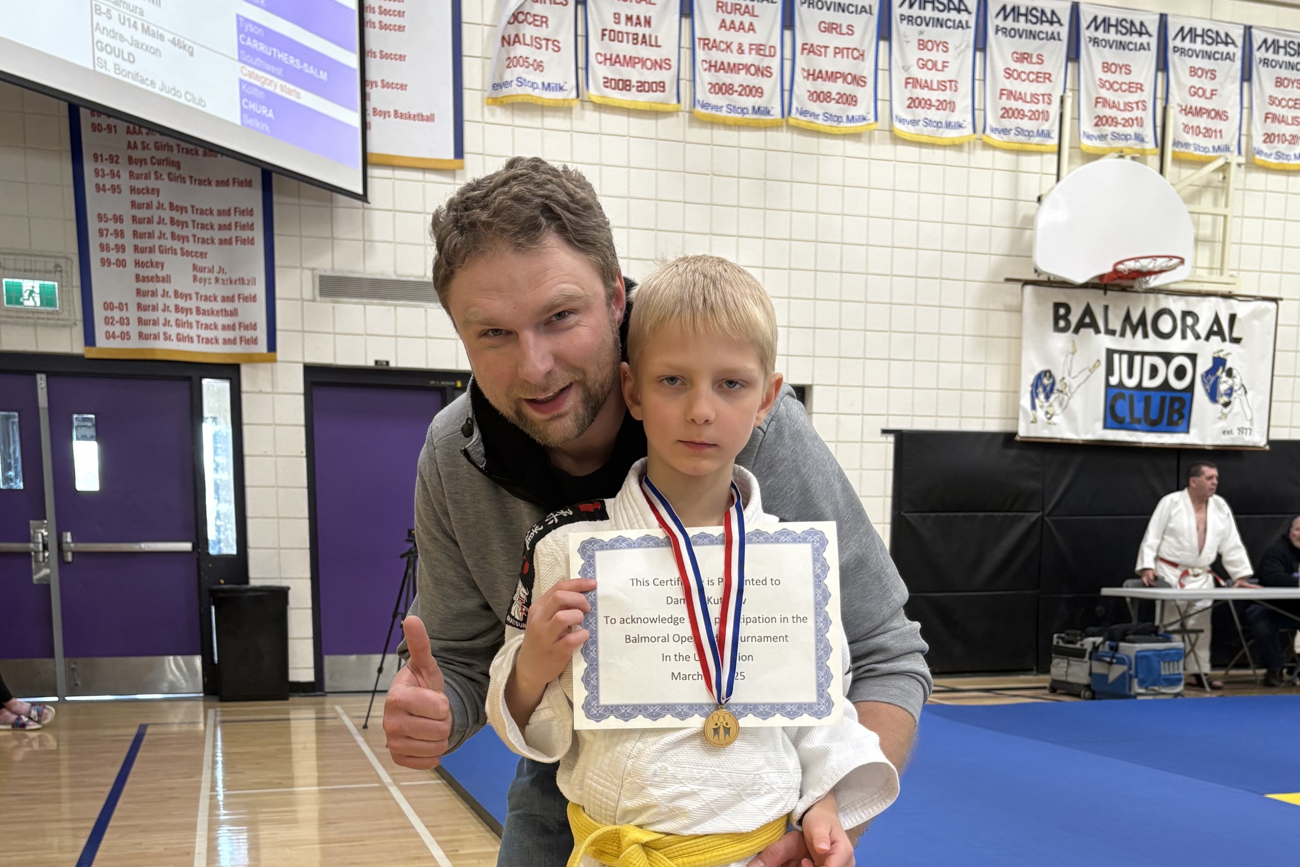 a father gives a thumbs-up to the camera with his son