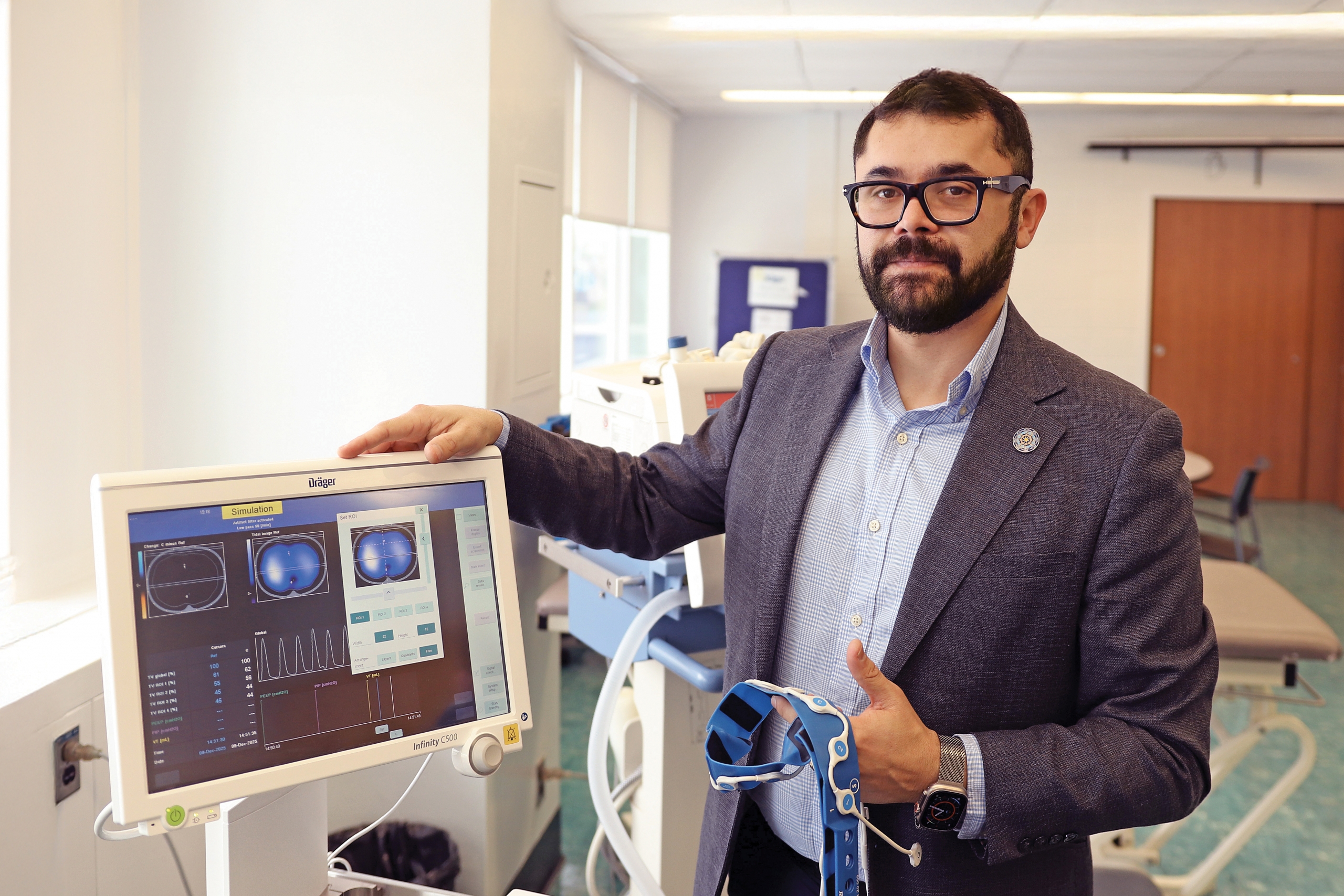 Mayson Sousa stands next to ventilation machine in a lab setting.
