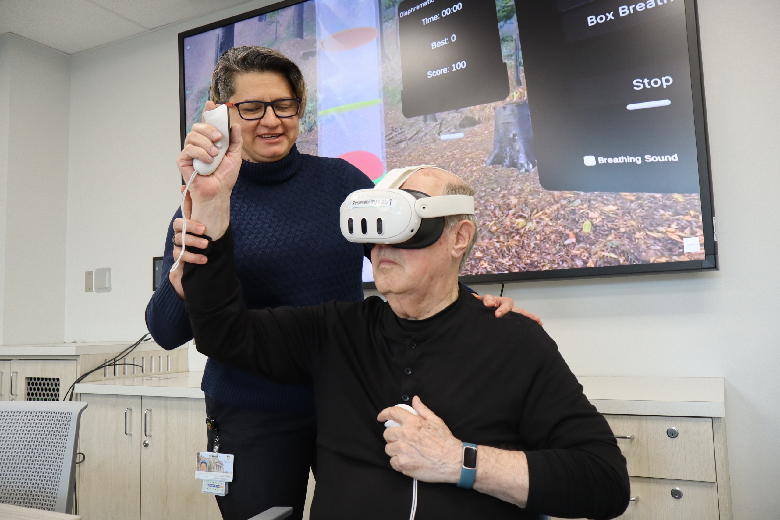 Diana Sanchez-Ramirez assists a patient research partner who is wearing a virtual reality headset.
