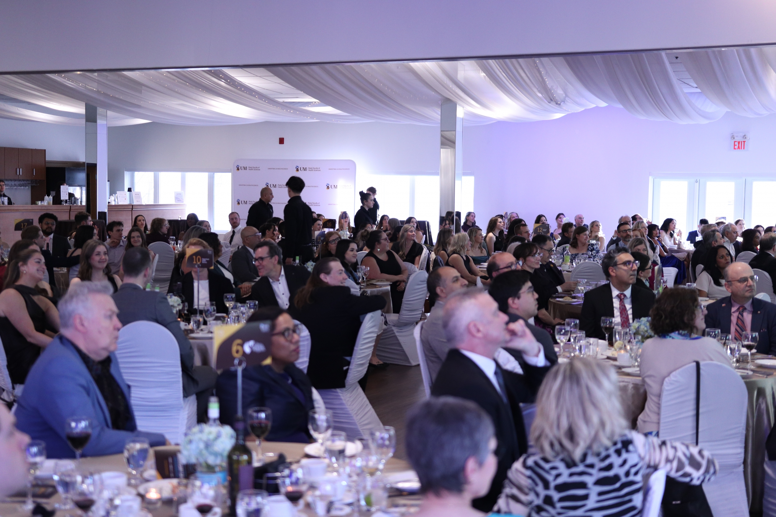 The crowd seated at round tables at the gala. 