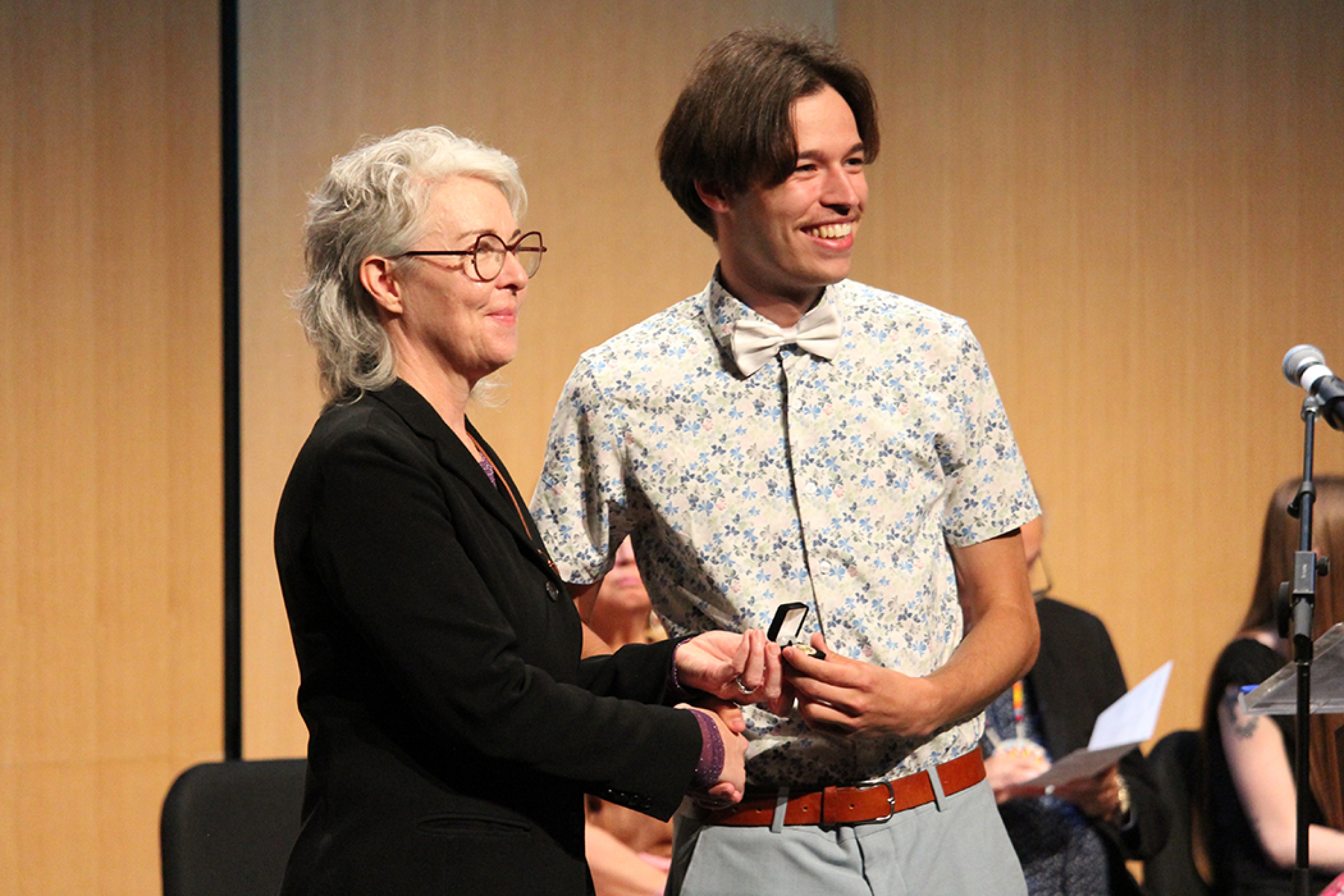 College of Nursing dean Kellie Thiessen presents Judah Chepil with his nursing pin.