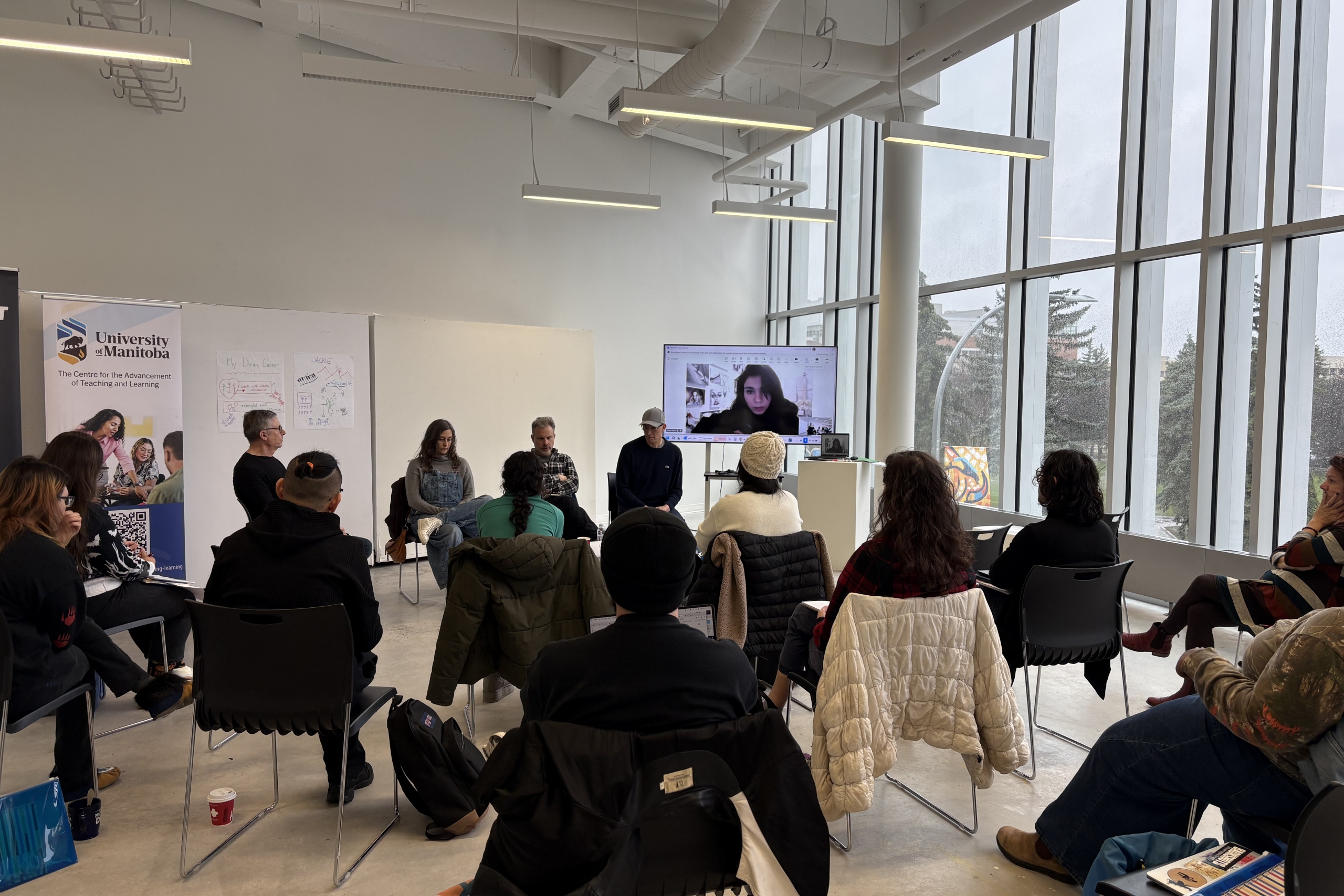 Several people sitting in chairs listening to the speakers at the front of the room.