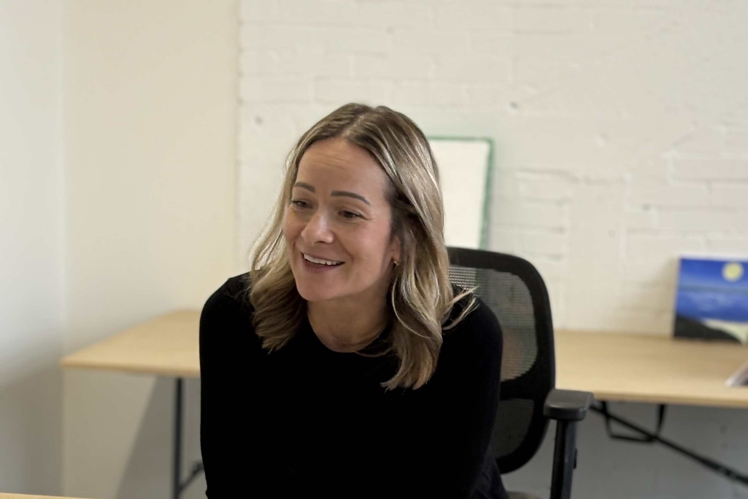 A smiling person sitting at a table.