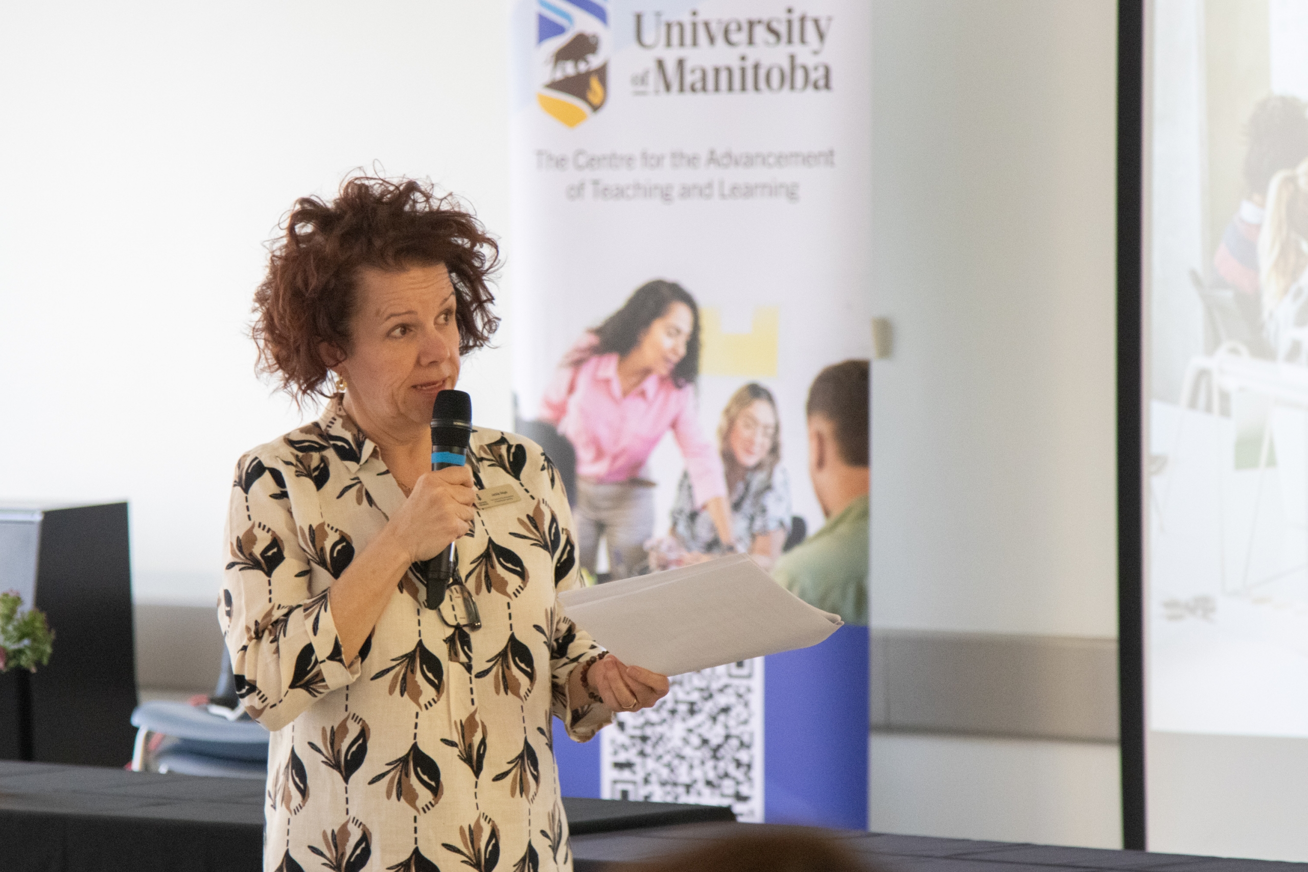 A woman is holding a microphone, moderating the panel.