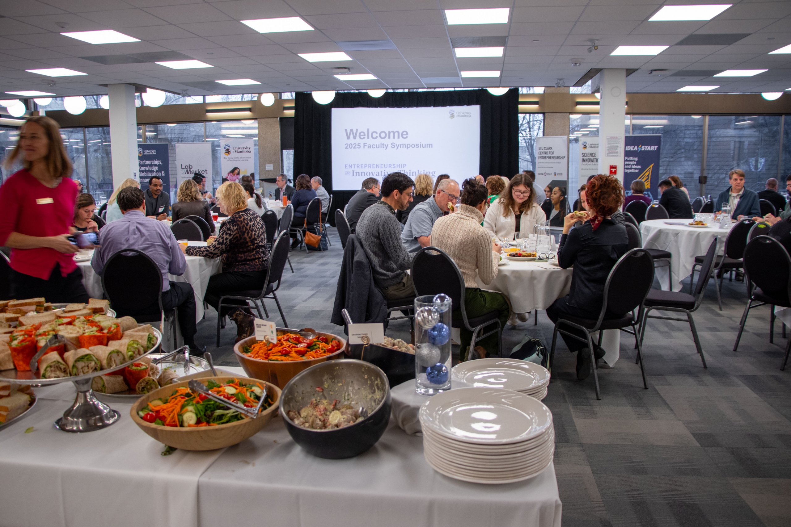 Faculty members sitting at tables and enjoying lunch at the 2025 Faculty Symposium