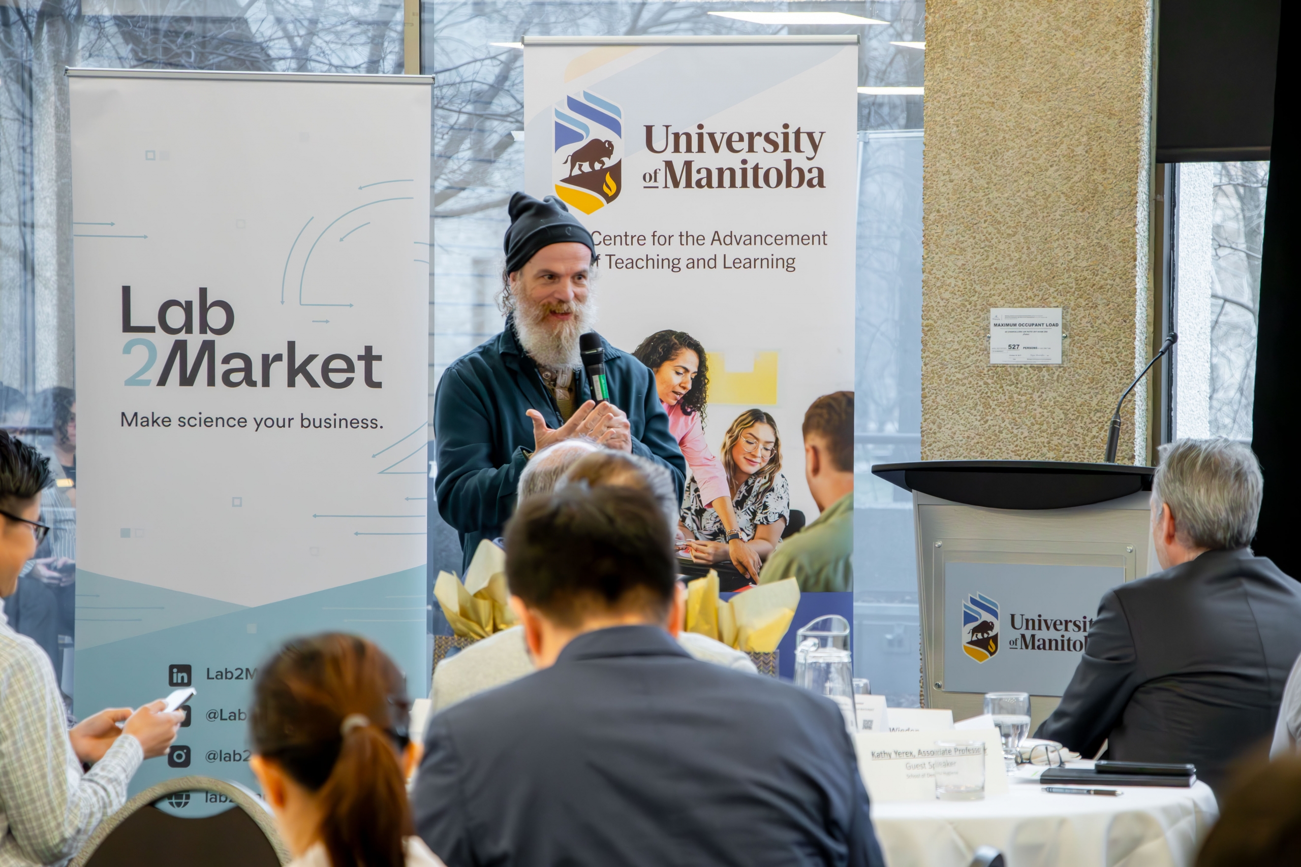 A speaker standing on stage presenting at the Faculty Symposium.