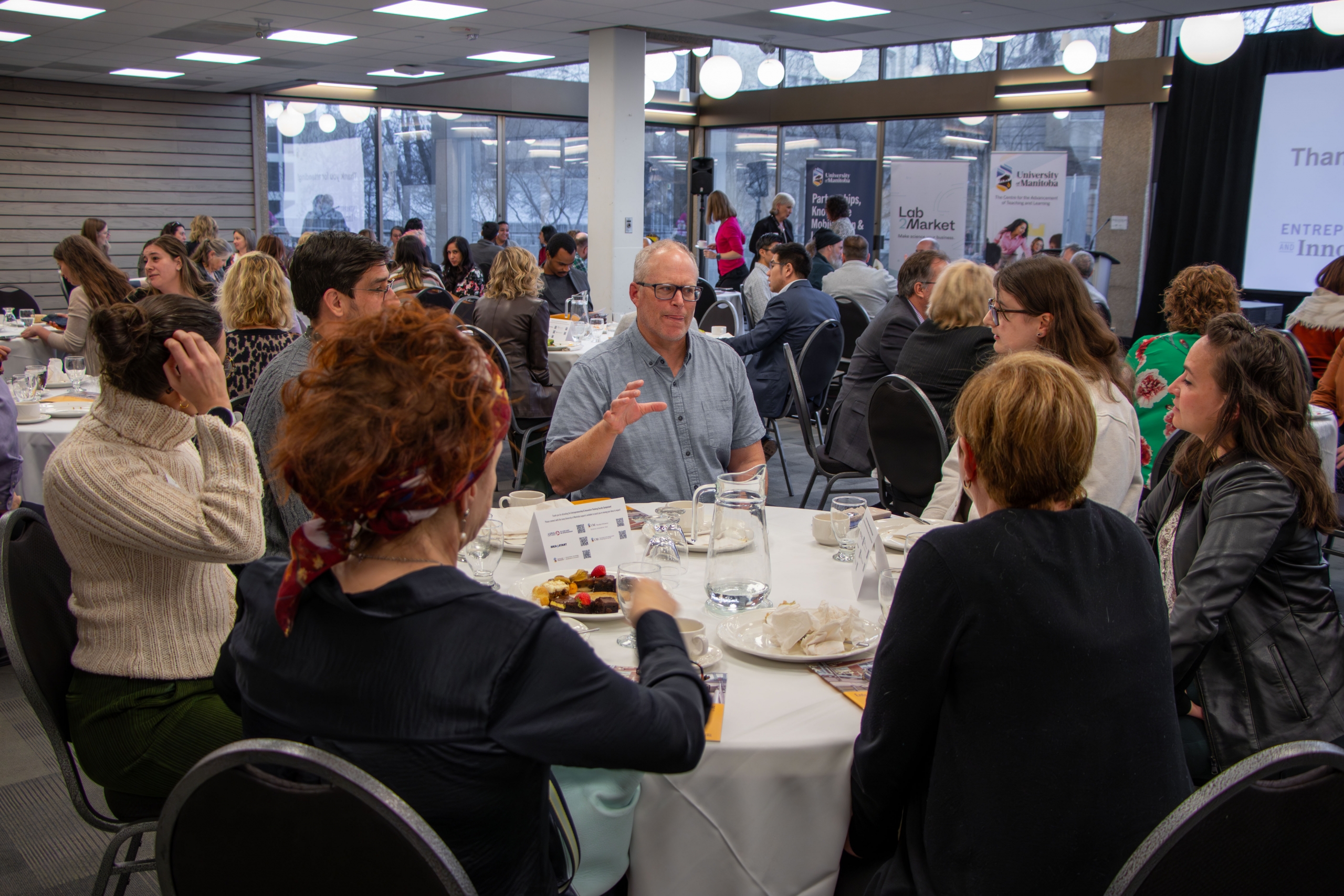Faculty members sitting at a circular table talking and having lunch.