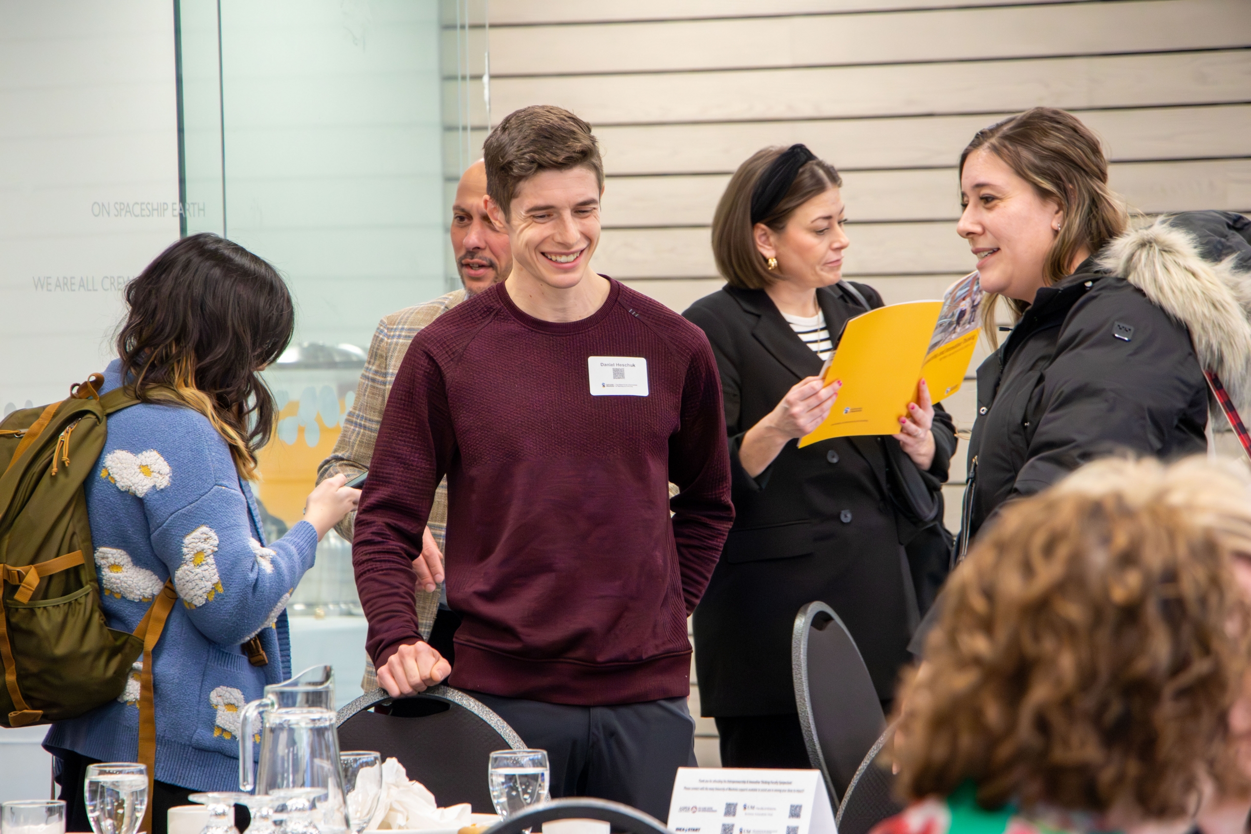 People smiling and having a conversation at the 2025 Faculty Symposium.
