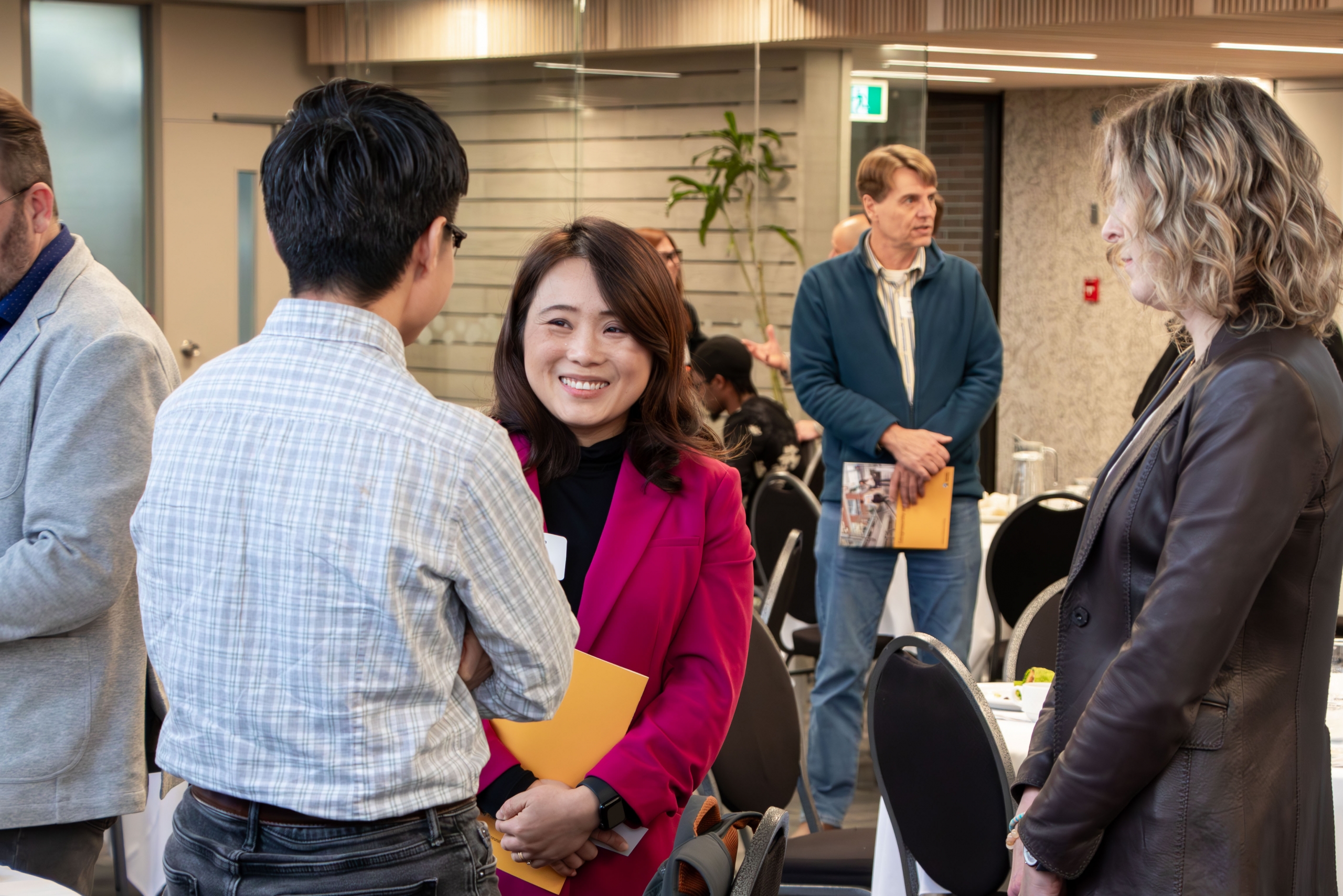 A smiling faculty member chatting with two other attendees.