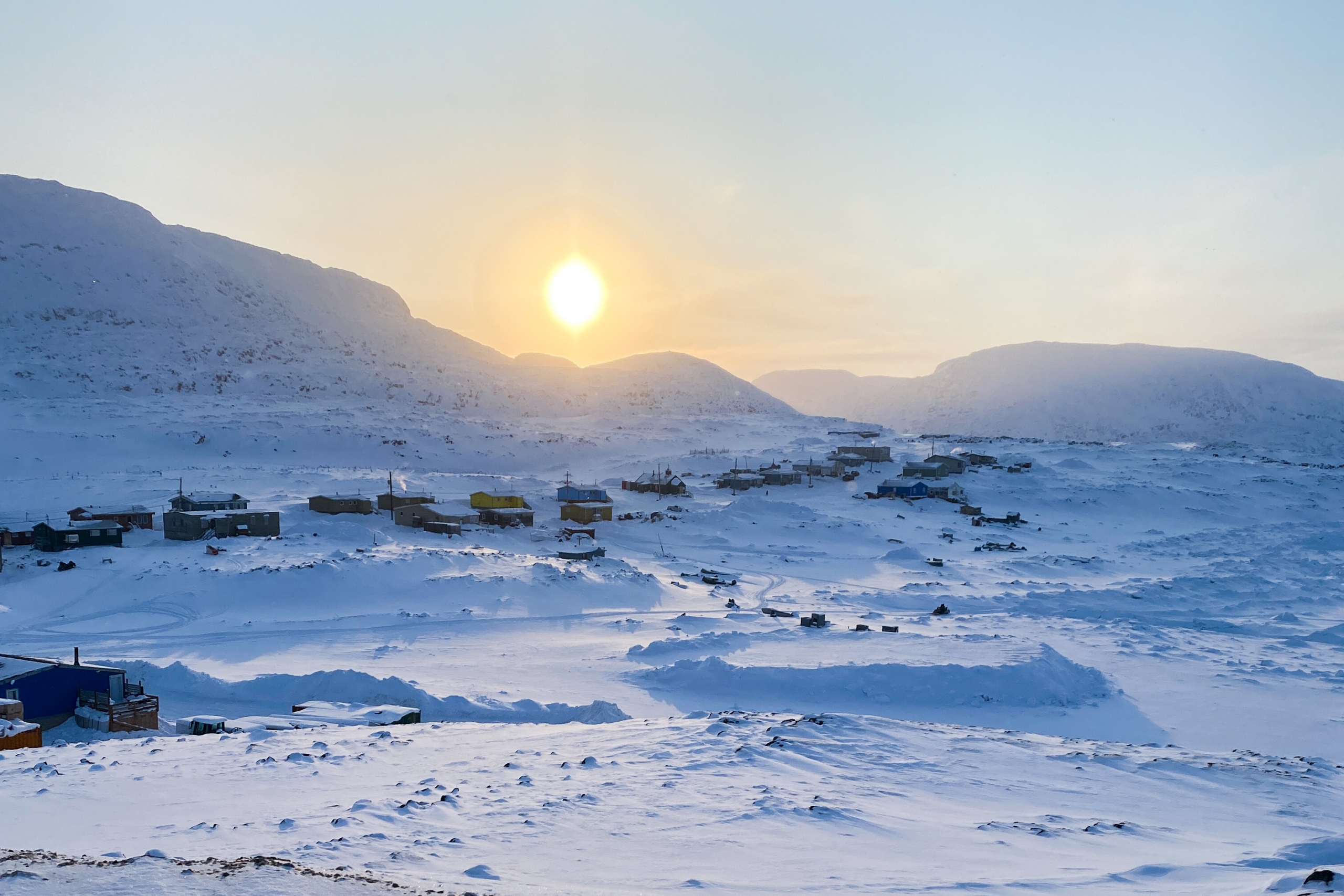 The sun rises over a snowy expanse.
