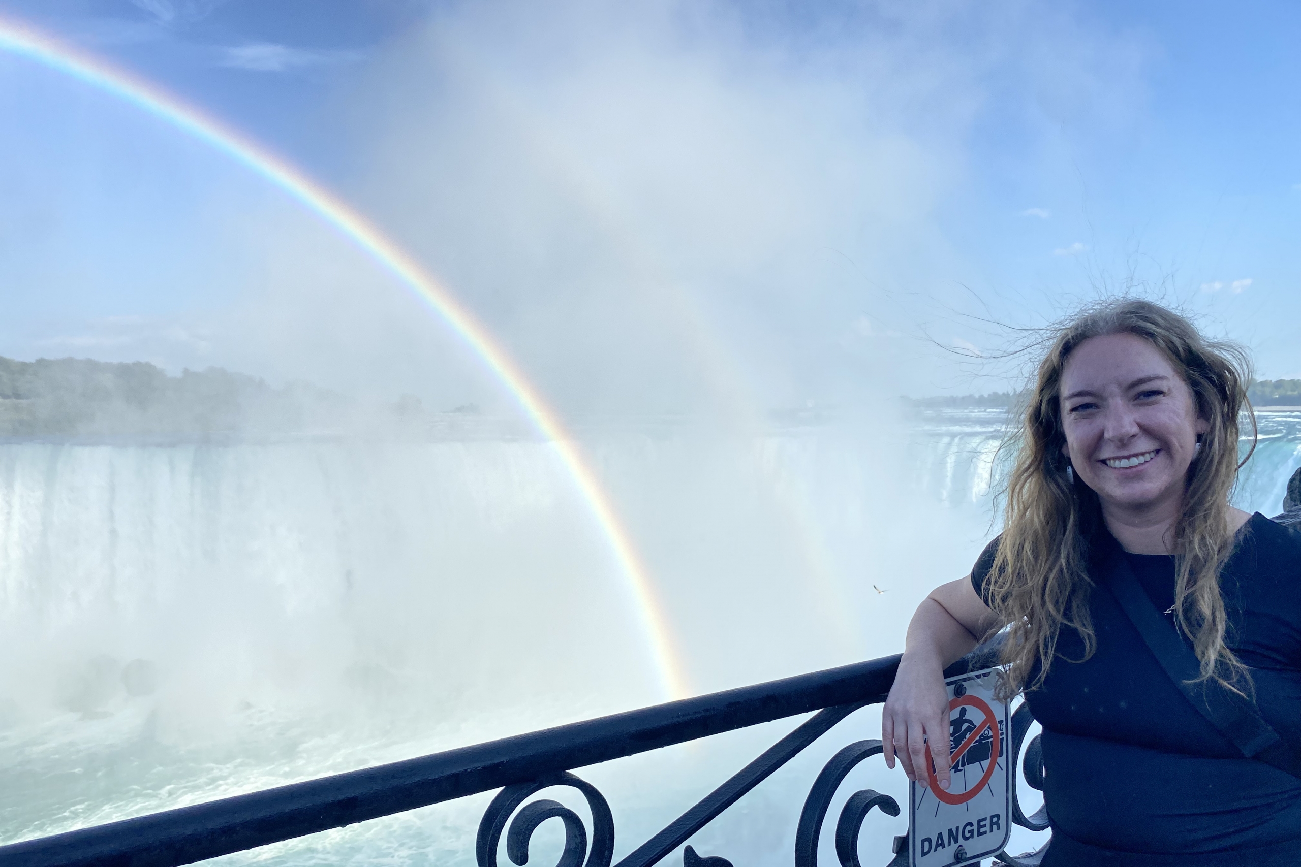 Maggie Cascadden stands at Niagara Falls with a rainbow