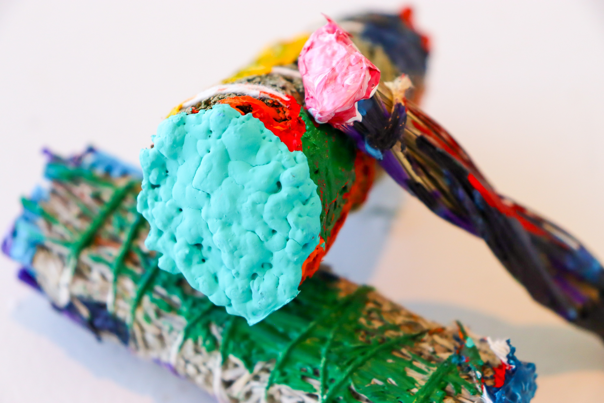Close-up of a brightly coloured mixed-media sculpture with textured surfaces and layered materials.