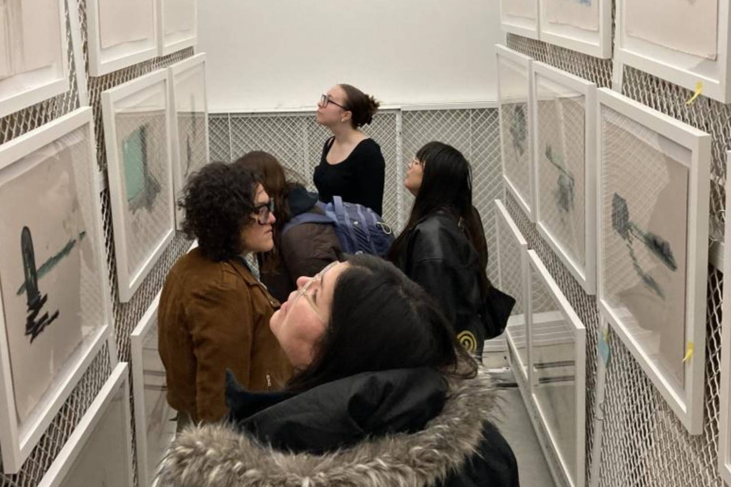 A group of people looking at a variety of artworks.