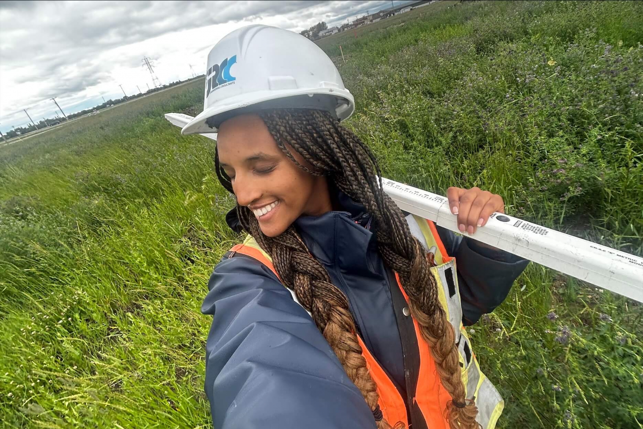 A person in a safety vest and hard hat standing in a field